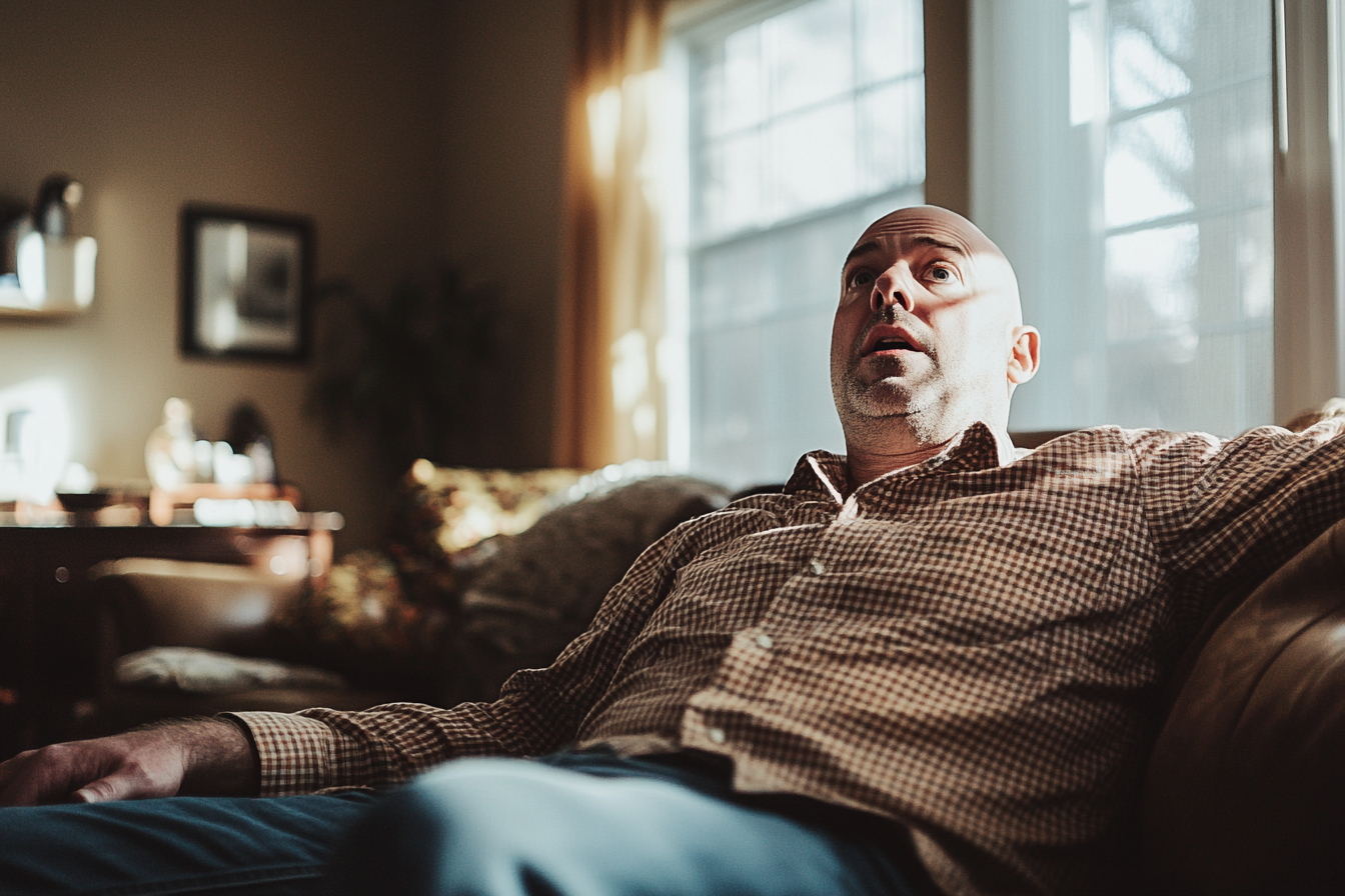 A man sitting on a couch, looking up worriedly | Source: Midjourney