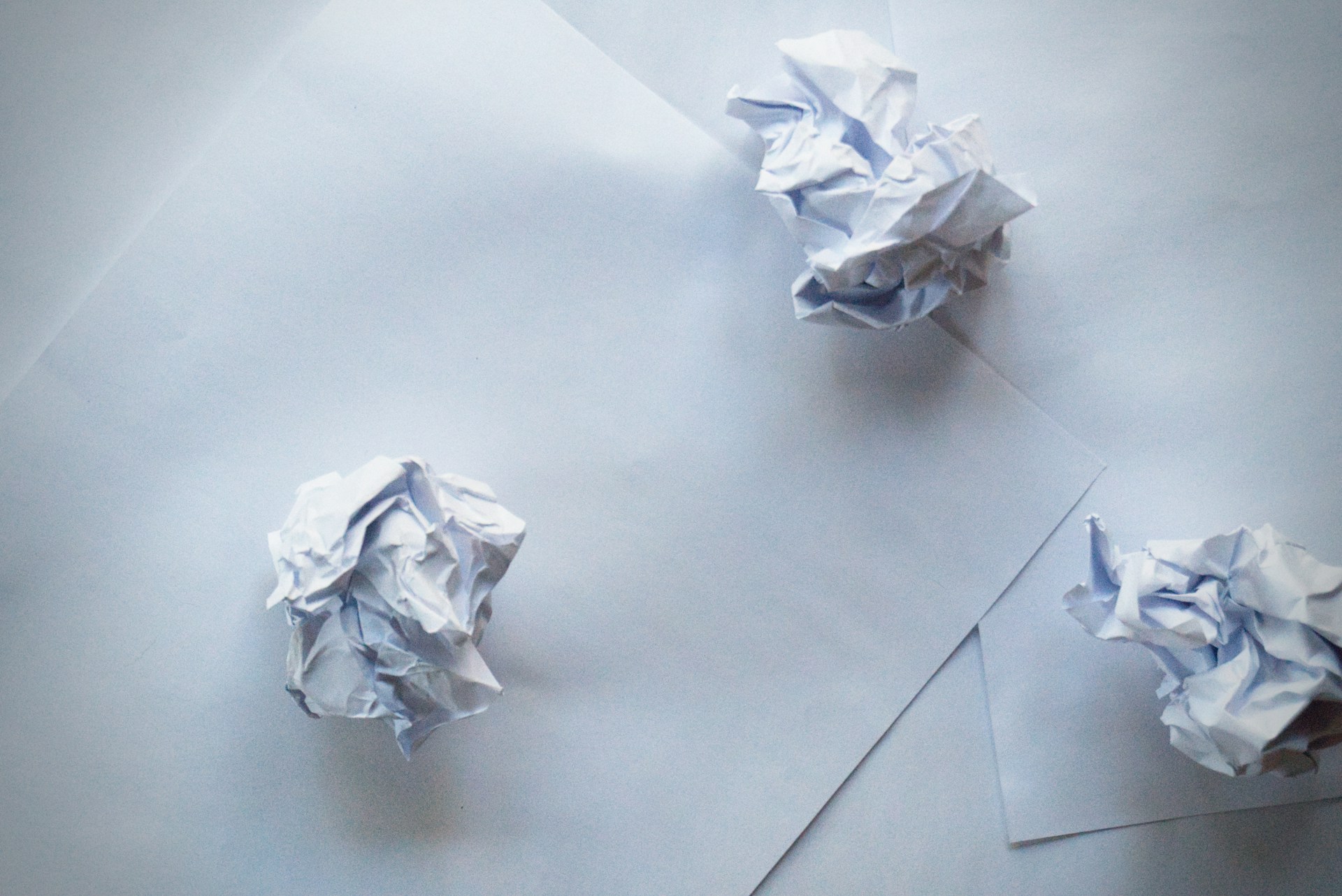 Crumpled paper balls and sheets of paper on a surface | Source: Unsplash