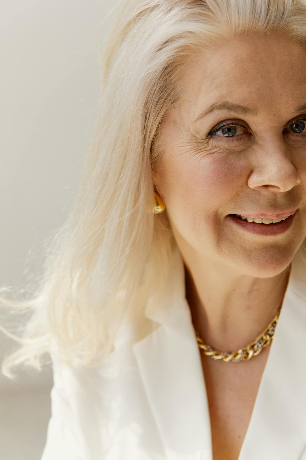 An elegantly dressed senior woman smiling | Source: Pexels