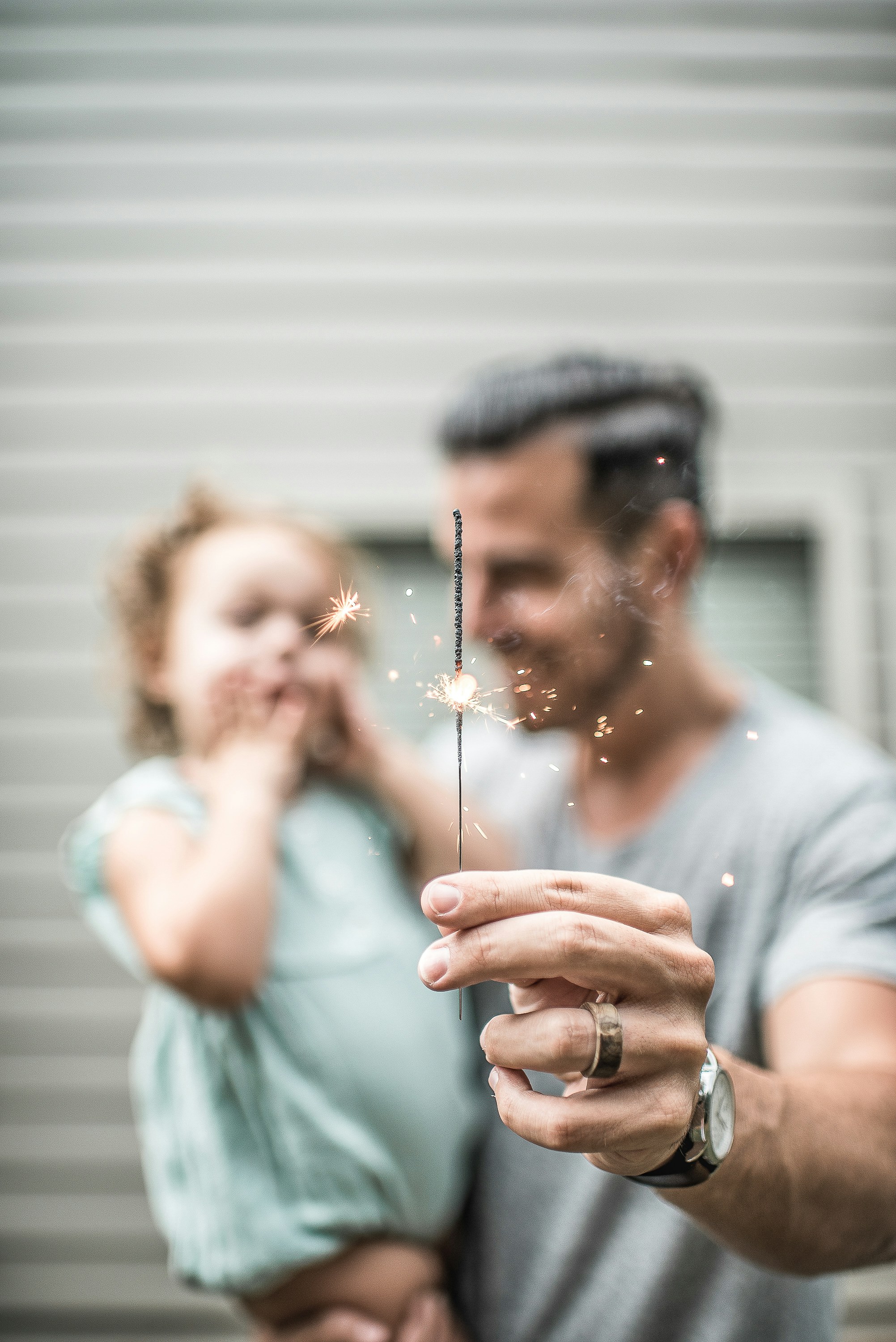 A close-up shot of a man with a little girl holding a sparkler | Source: Unsplash