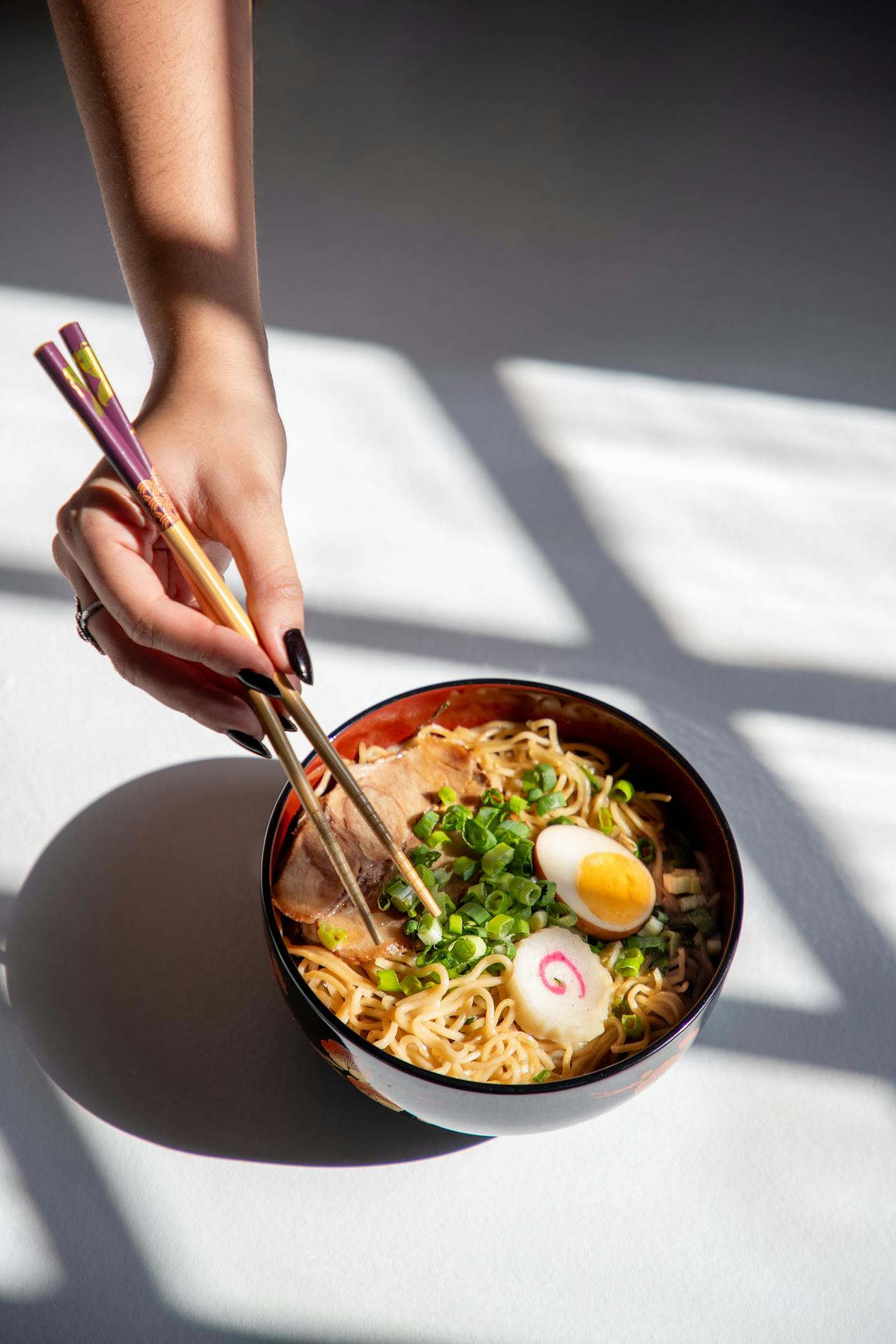 A woman holding chopsticks and eating ramen | Source: Pexels