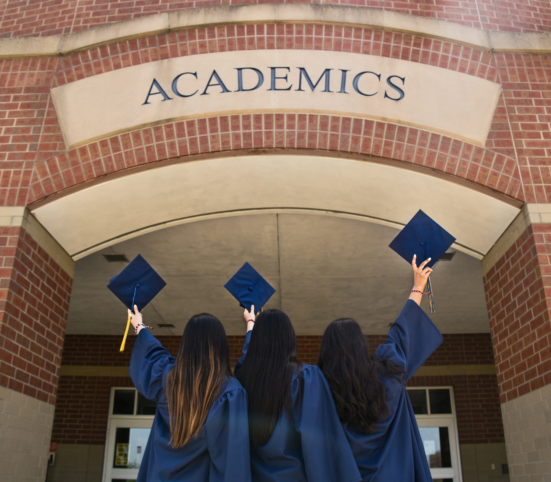 Young women standing in front of the academics block in their graduation gowns | Source: Unsplash