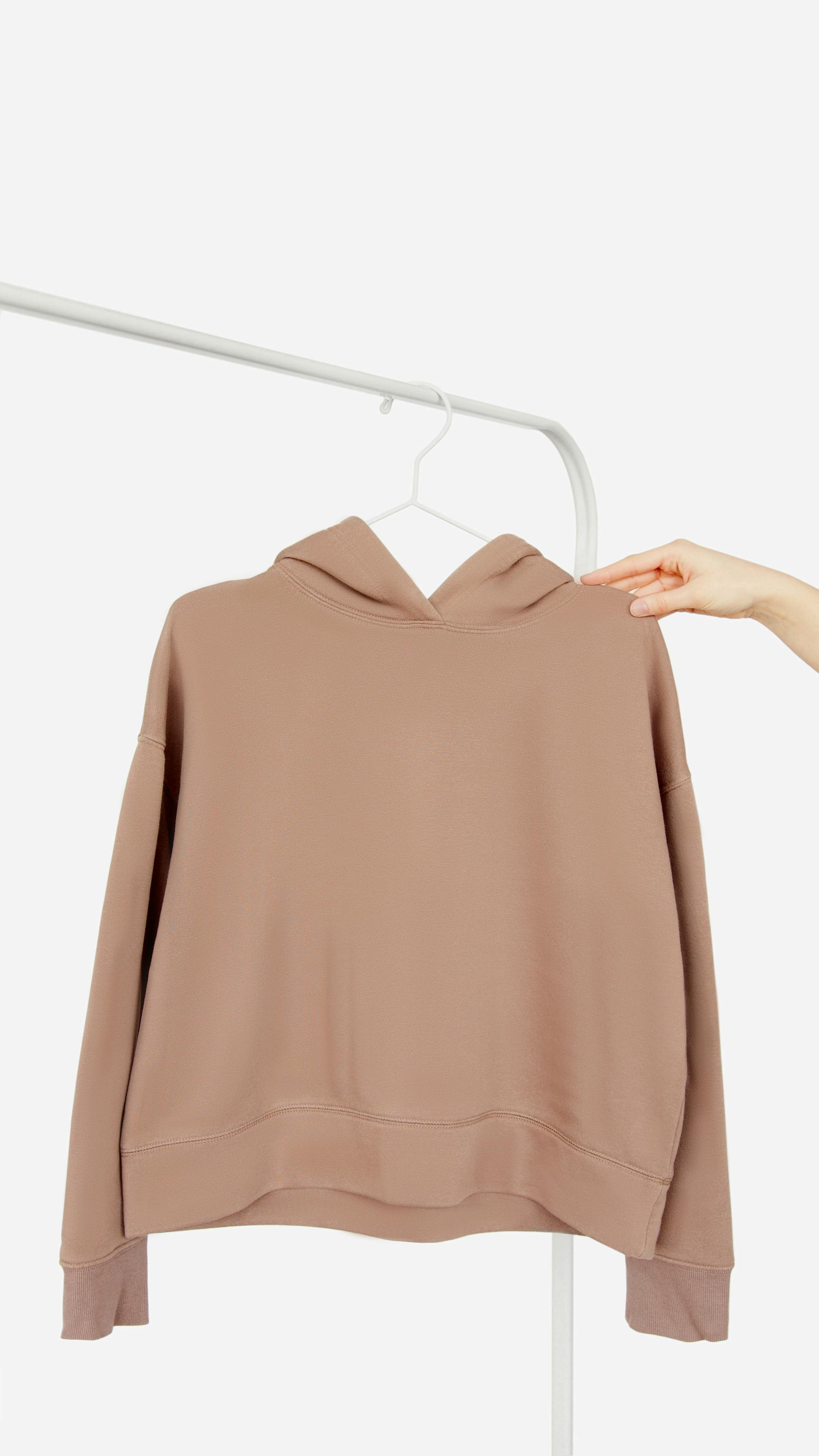 A person holding a dusty-pink hoodie | Source: Pexels