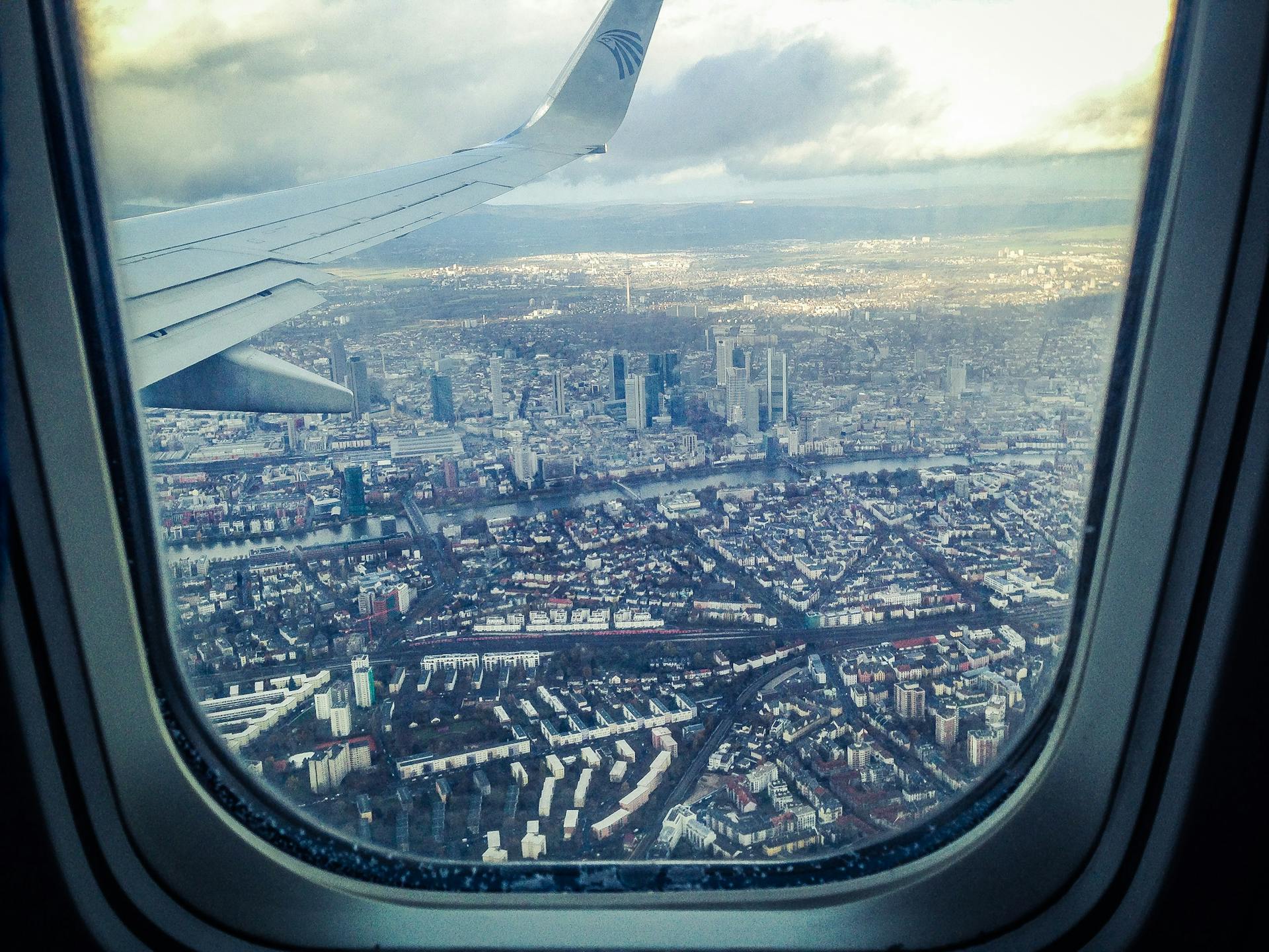 An airplane windowpane showing city buildings | Source: Pexels