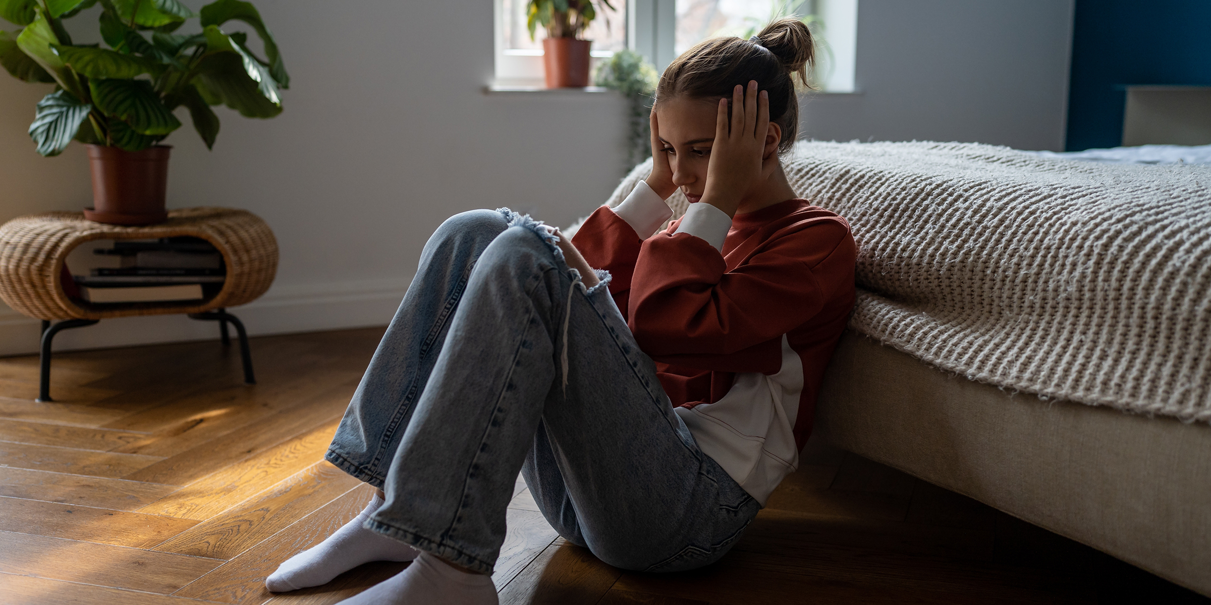 A distressed teenage girl sitting on the floor | Source: Shutterstock