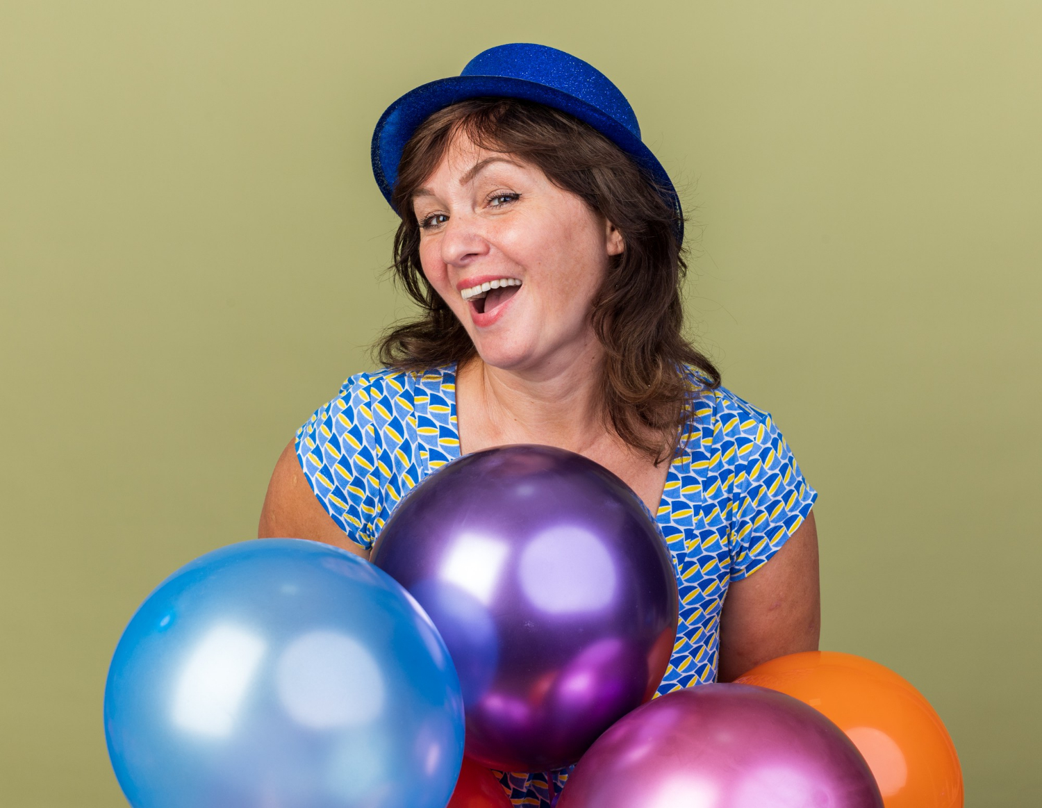 A cheerful middle-aged woman holding colorful balloons | Source: Freepik