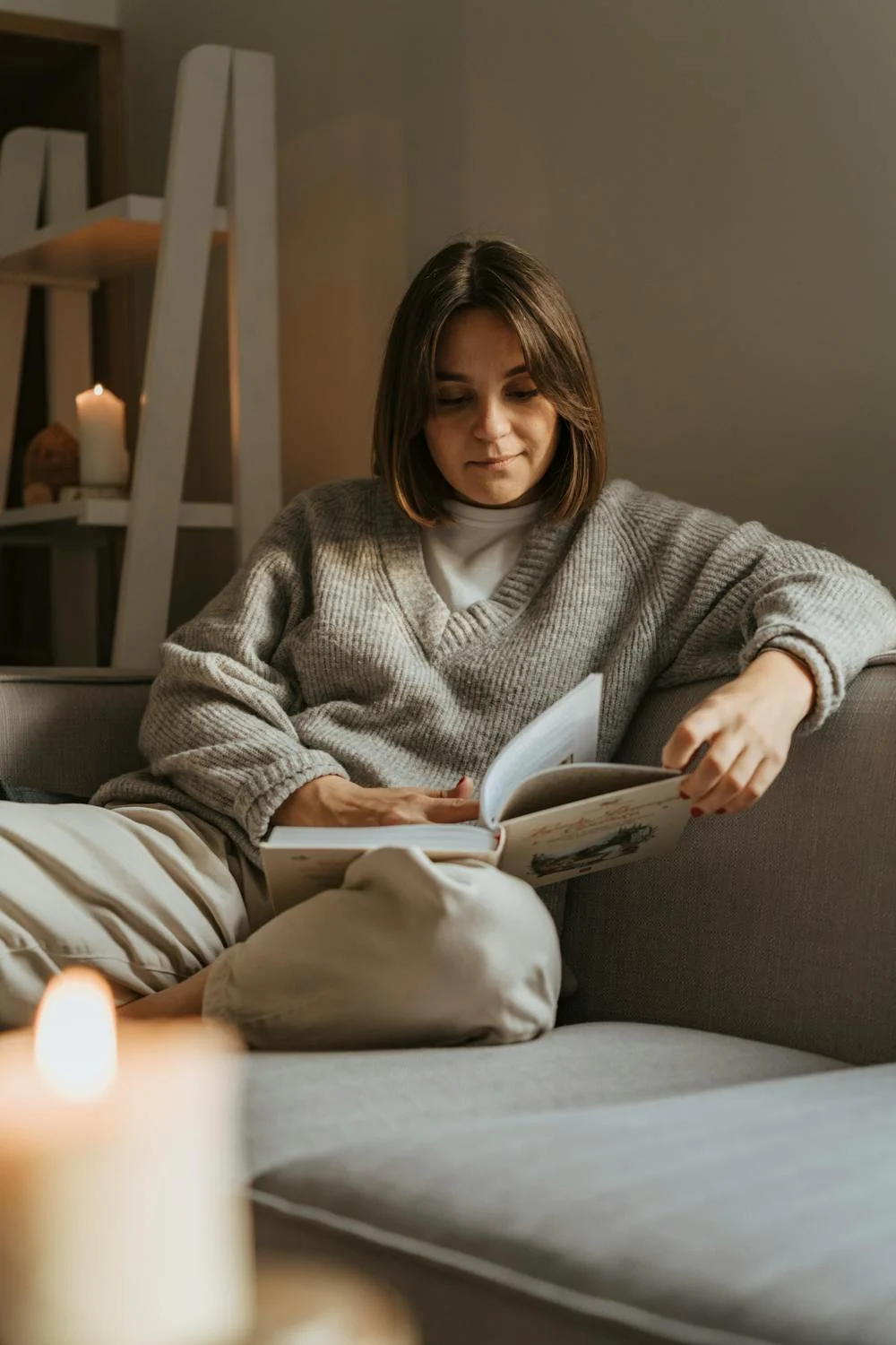 A woman reading a book on a couch | Source: Pexels