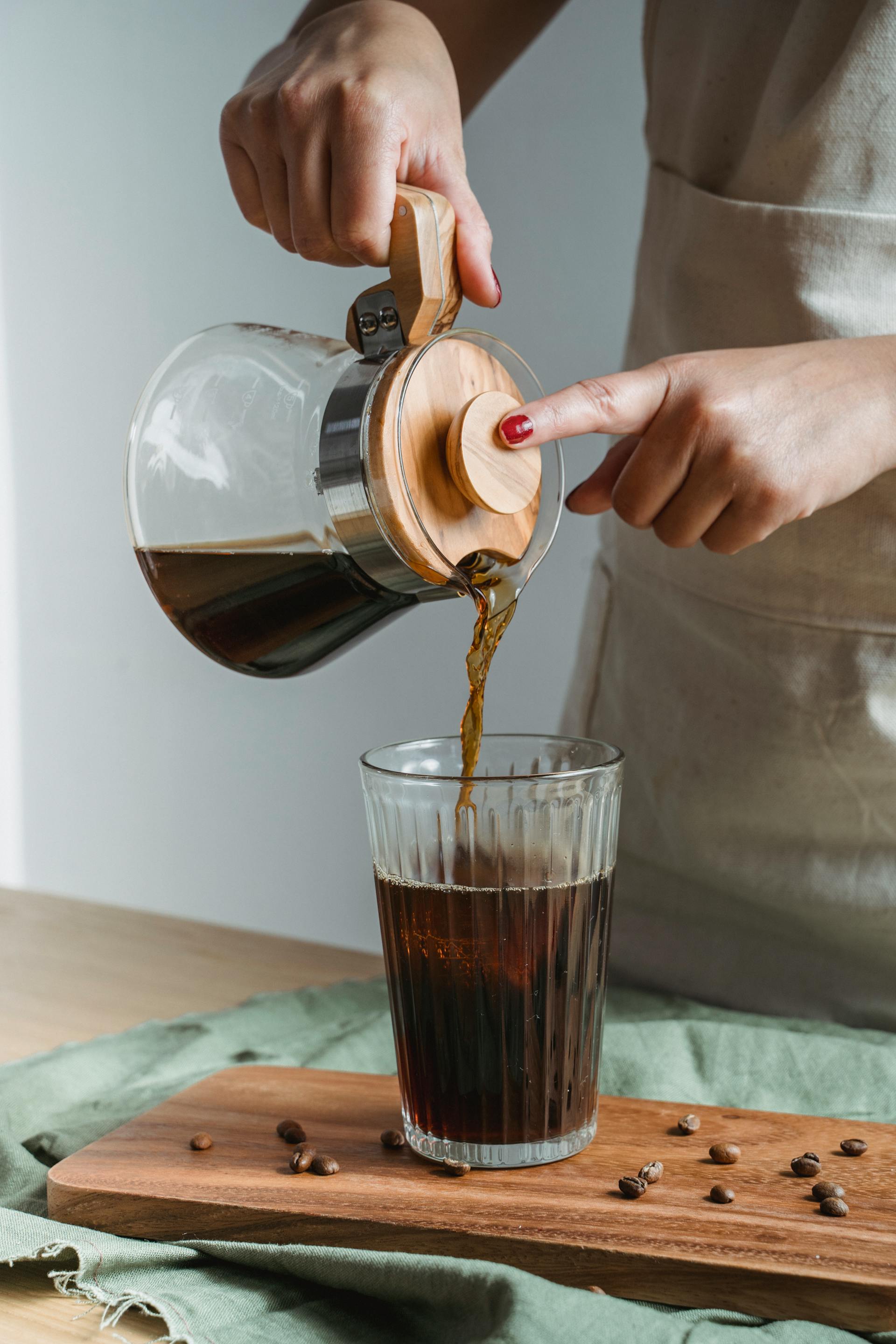A woman pouring black coffee in a glass | Source: Pexels