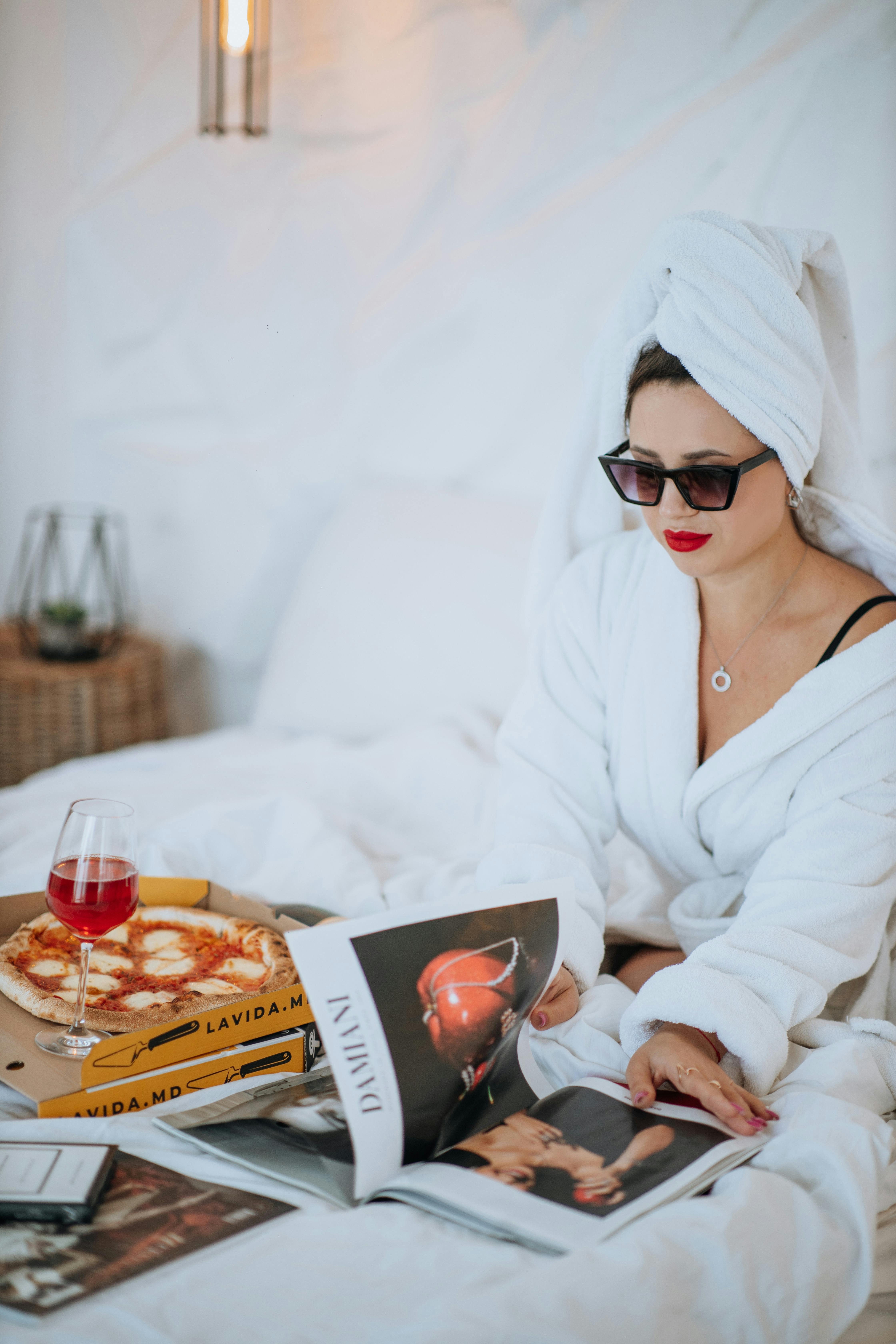 A woman in a robe having pizza in bed | Source: Pexels