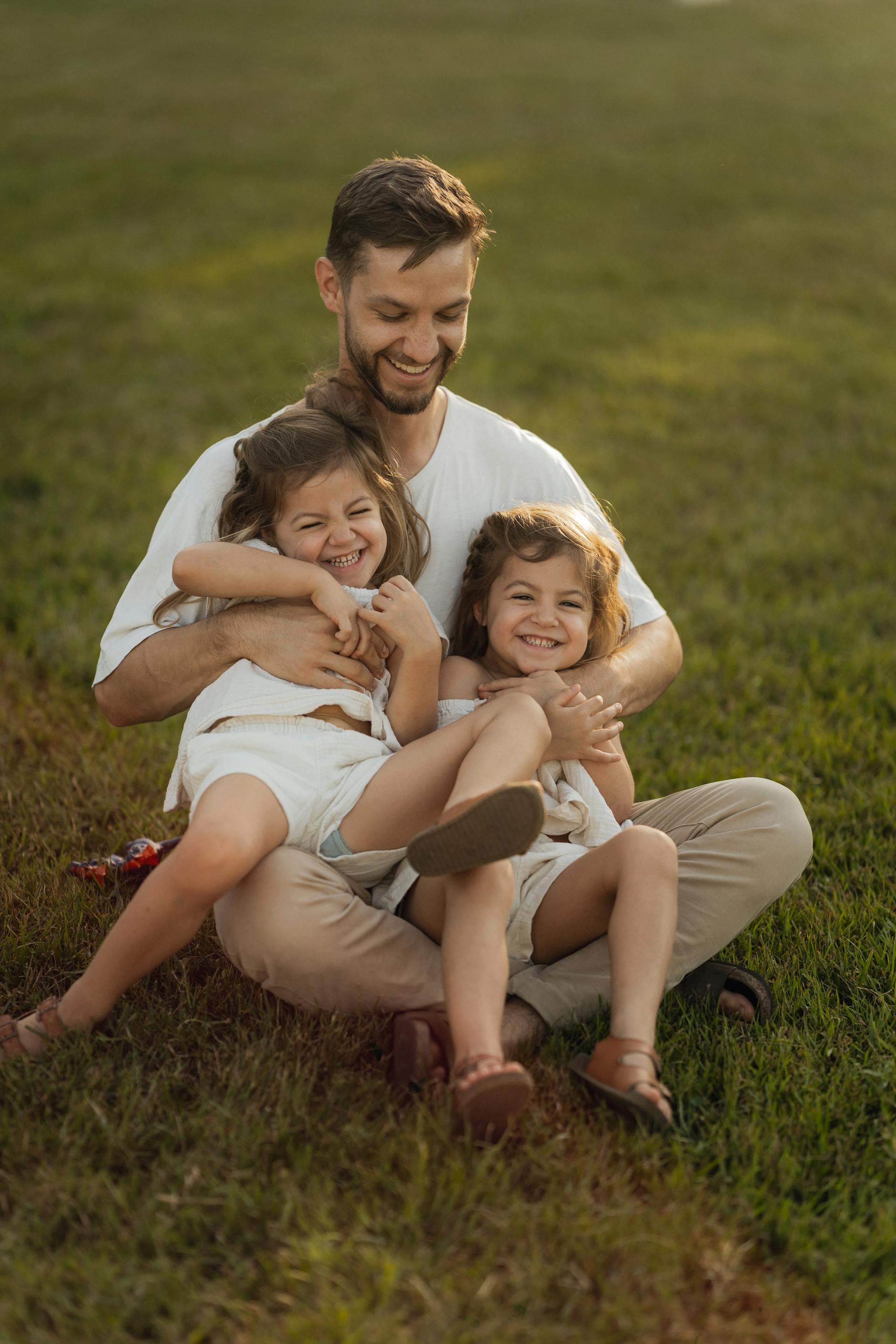A father playing with his daughters on the lawn | Source: Pexels