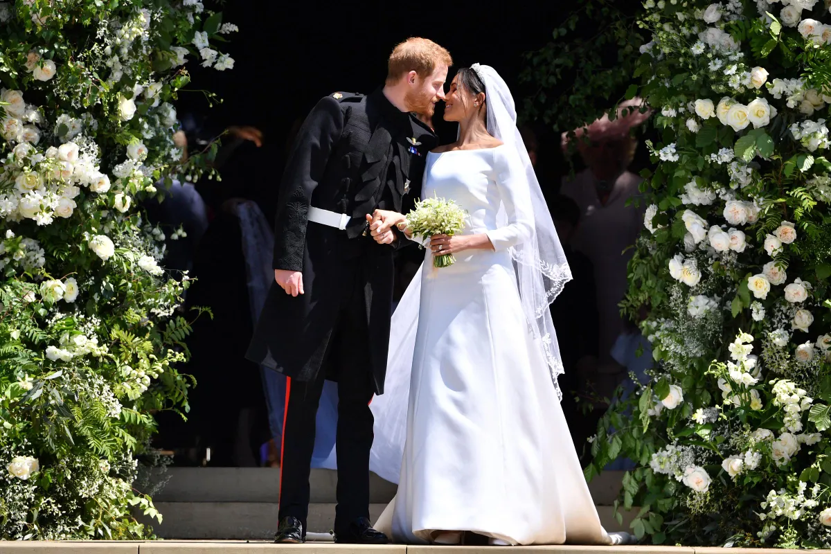 Prince Harry, Duke of Sussex kisses his wife Meghan, Duchess of Sussex as they leave from the West Door of St George's Chapel, Windsor Castle, in Windsor, on May 19, 2018. | Source: Getty Images