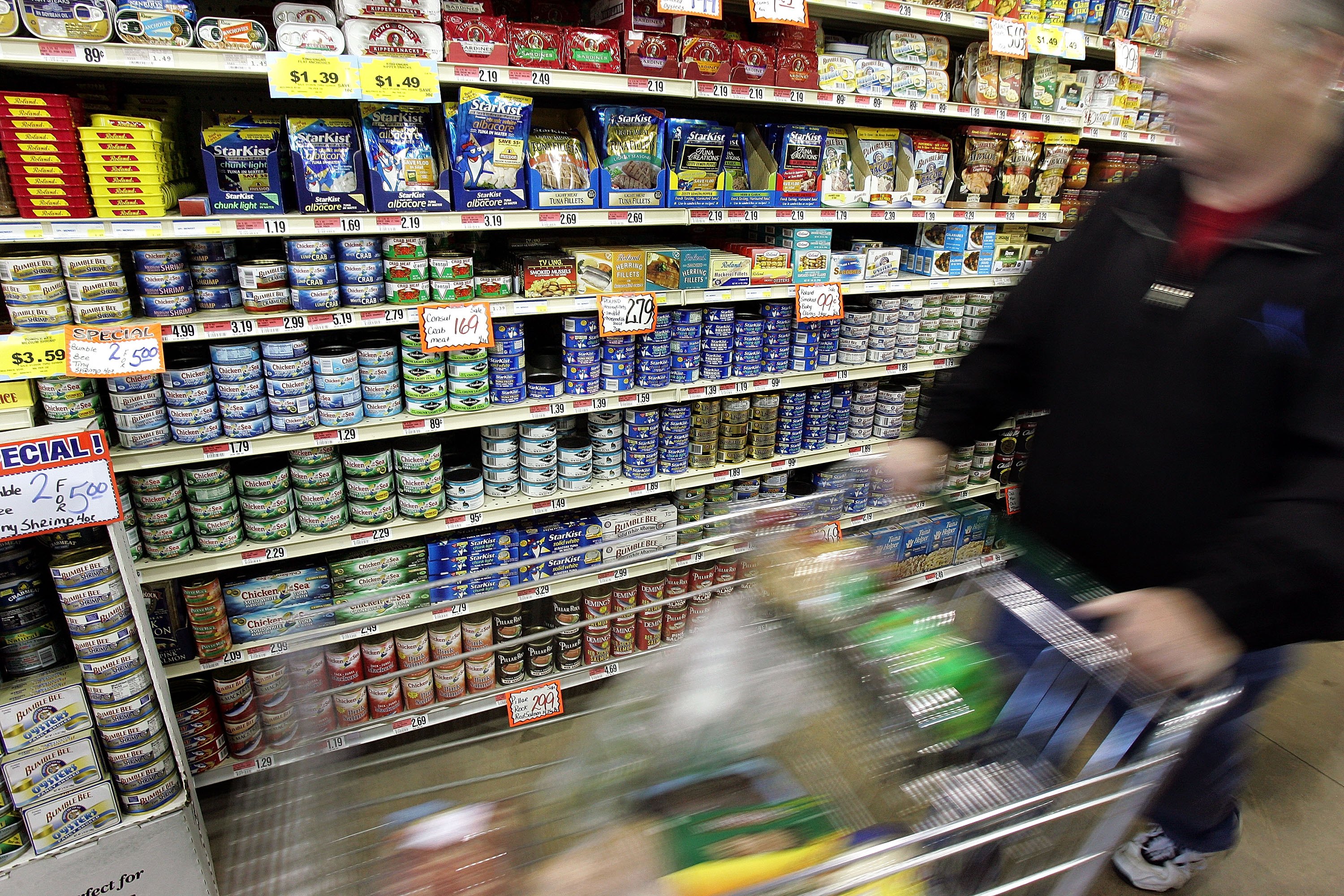 A shopper walks by cans of tuna fish on display in a grocery store in Des Plaines, Illinois, on January 27, 2006 | Source: Getty Images