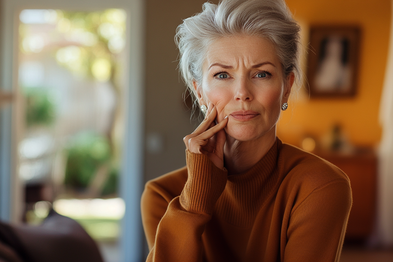 Elegant woman in her 60s looking worried in her living room | Source: Midjourney