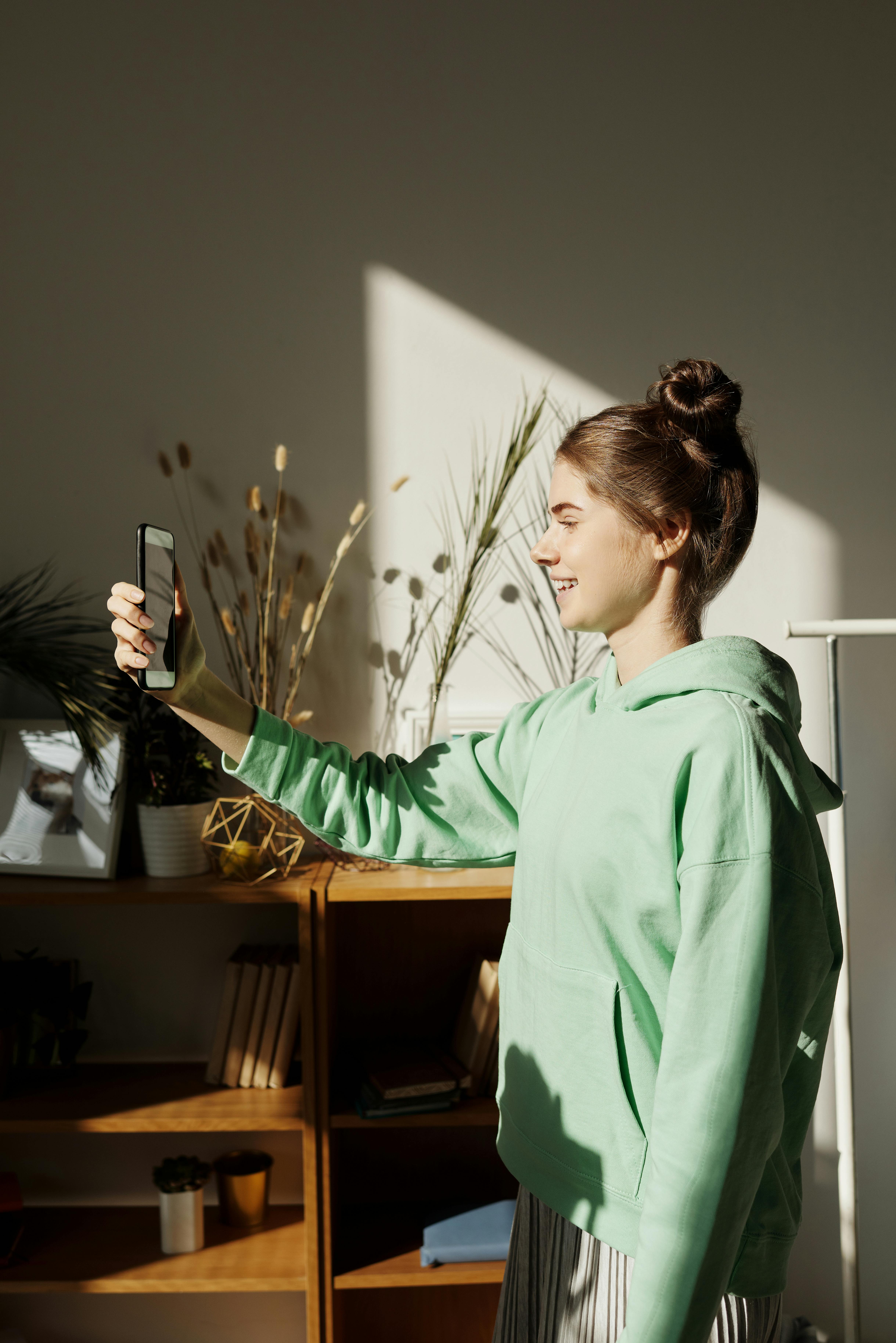 A girl laughing while recording with her phone | Source: Pexels
