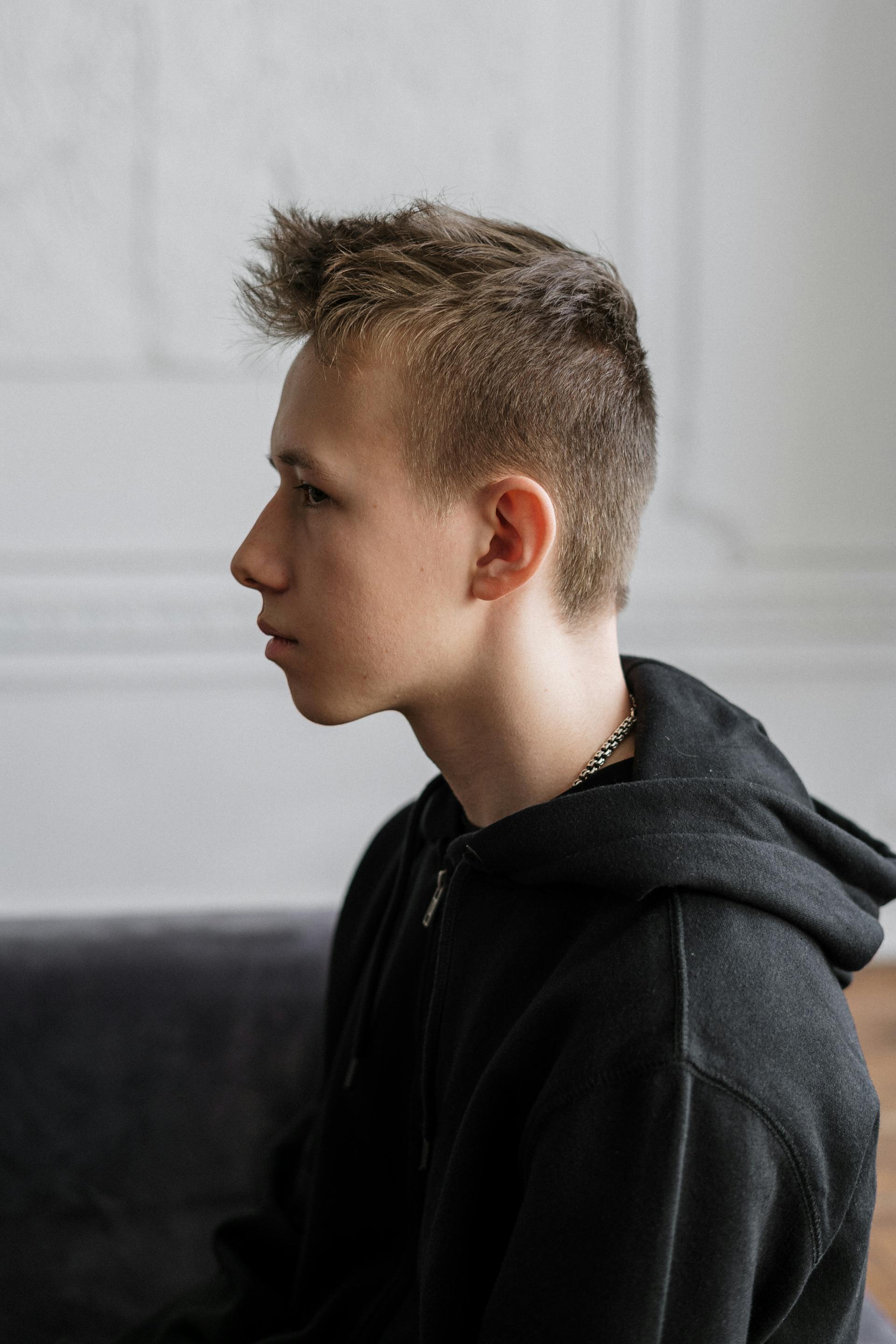 A thoughtful teen boy on a sofa | Source: Pexels