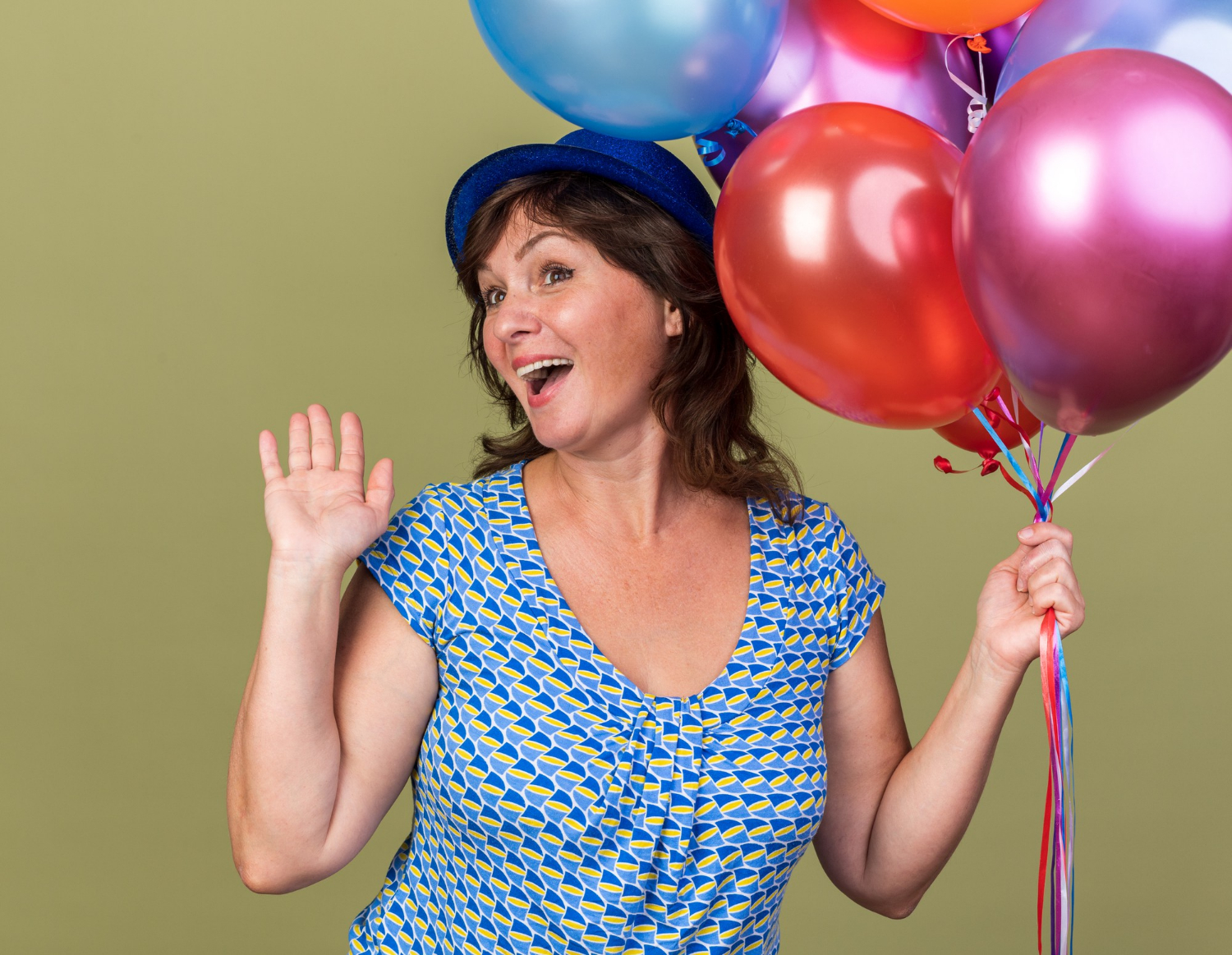 A delighted senior woman holding balloons | Source: Freepik