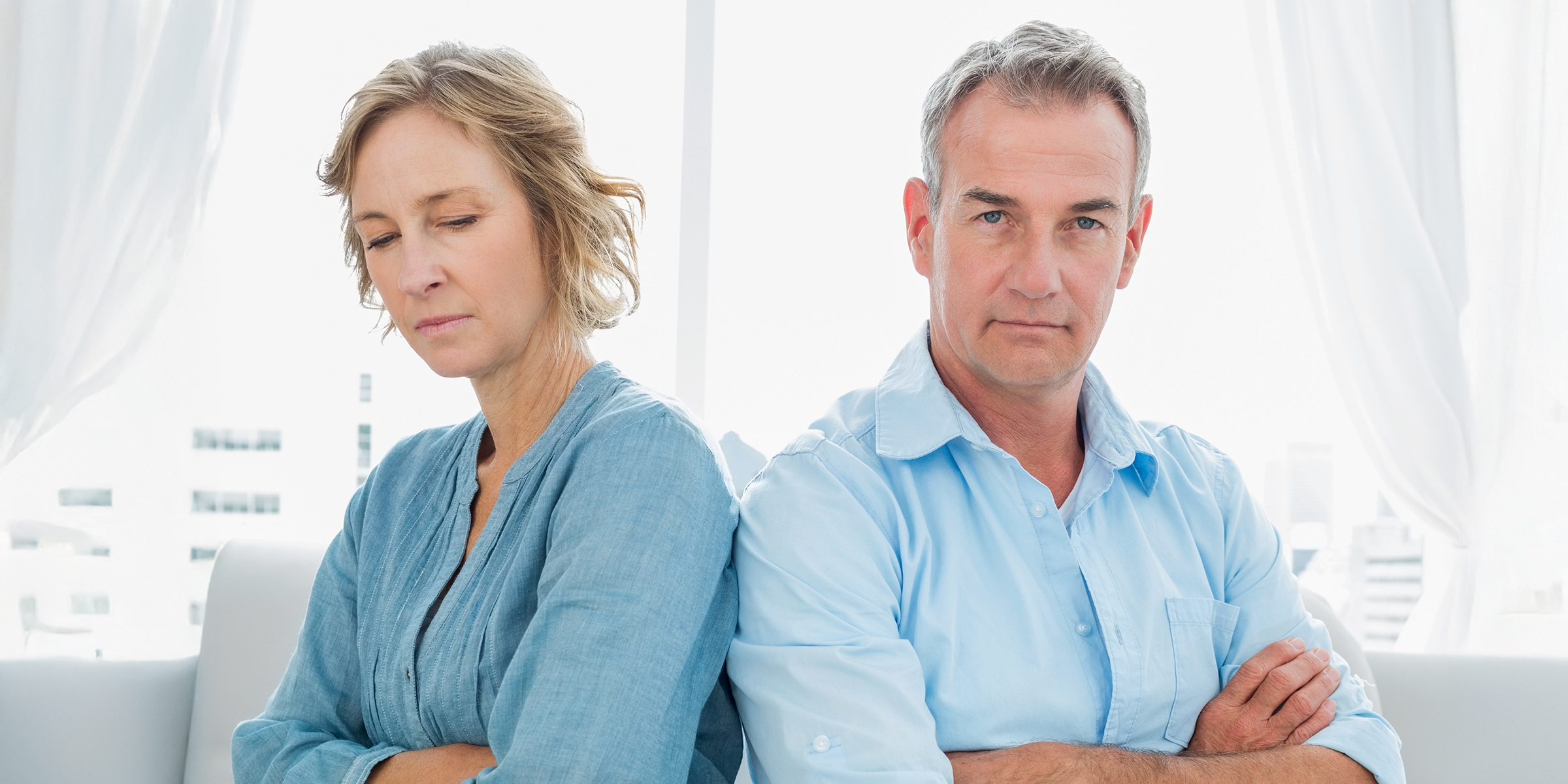 A tensed middle-aged couple sitting with arms crossed | Source: Shutterstock