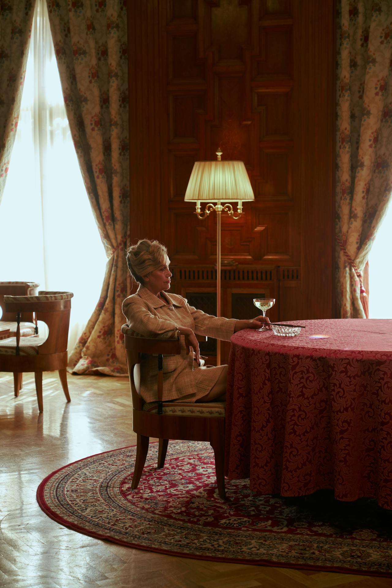 An elegant older woman seated at a table and holding a glass | Source: Pexels