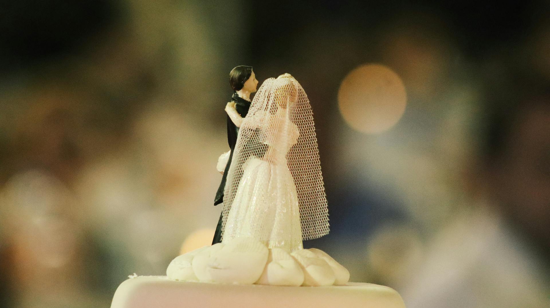 A bride and groom cake topper on a wedding cake | Source: Pexels