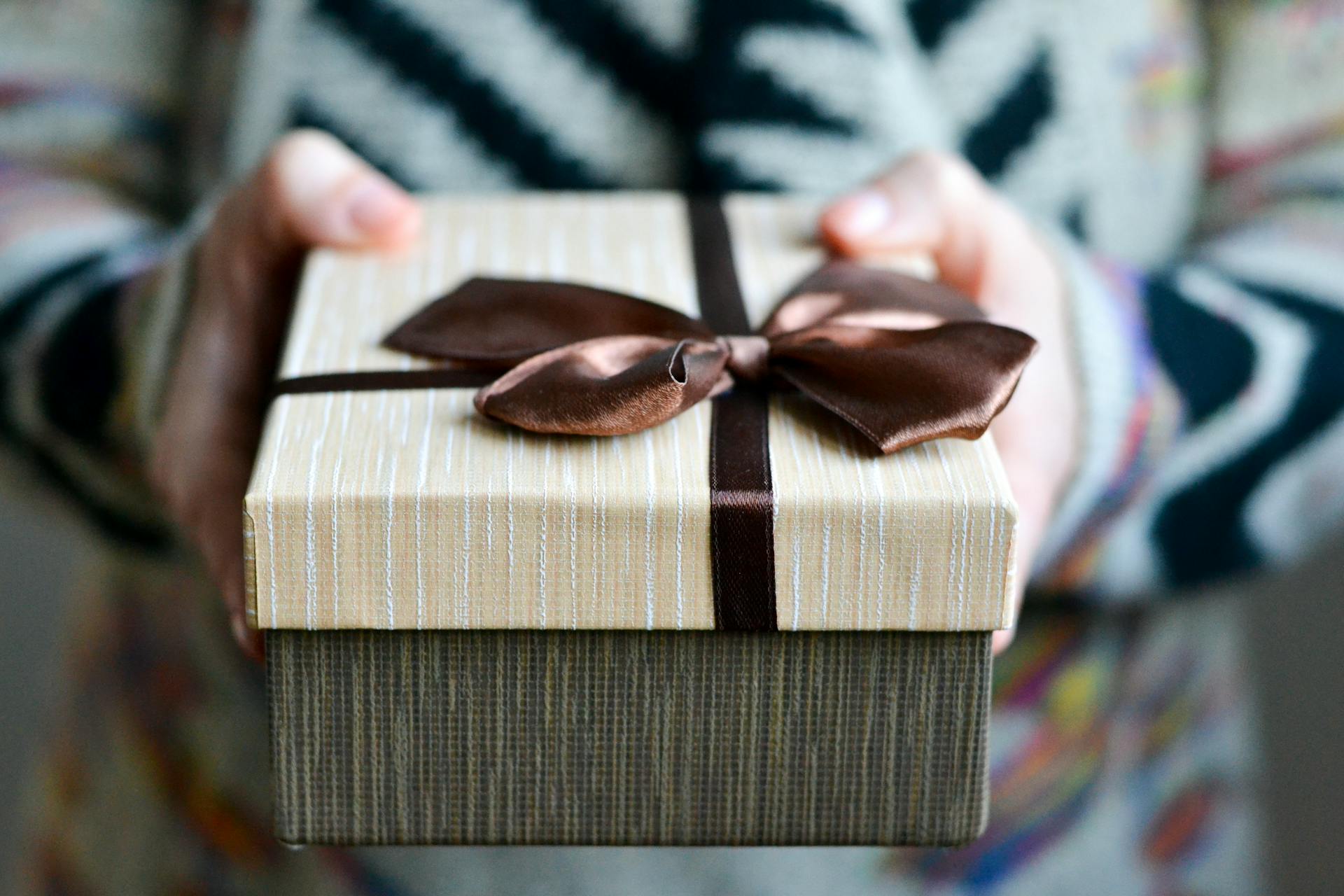 A close-up shot of a person holding a gift box with a brown ribbon | Source: Pexels