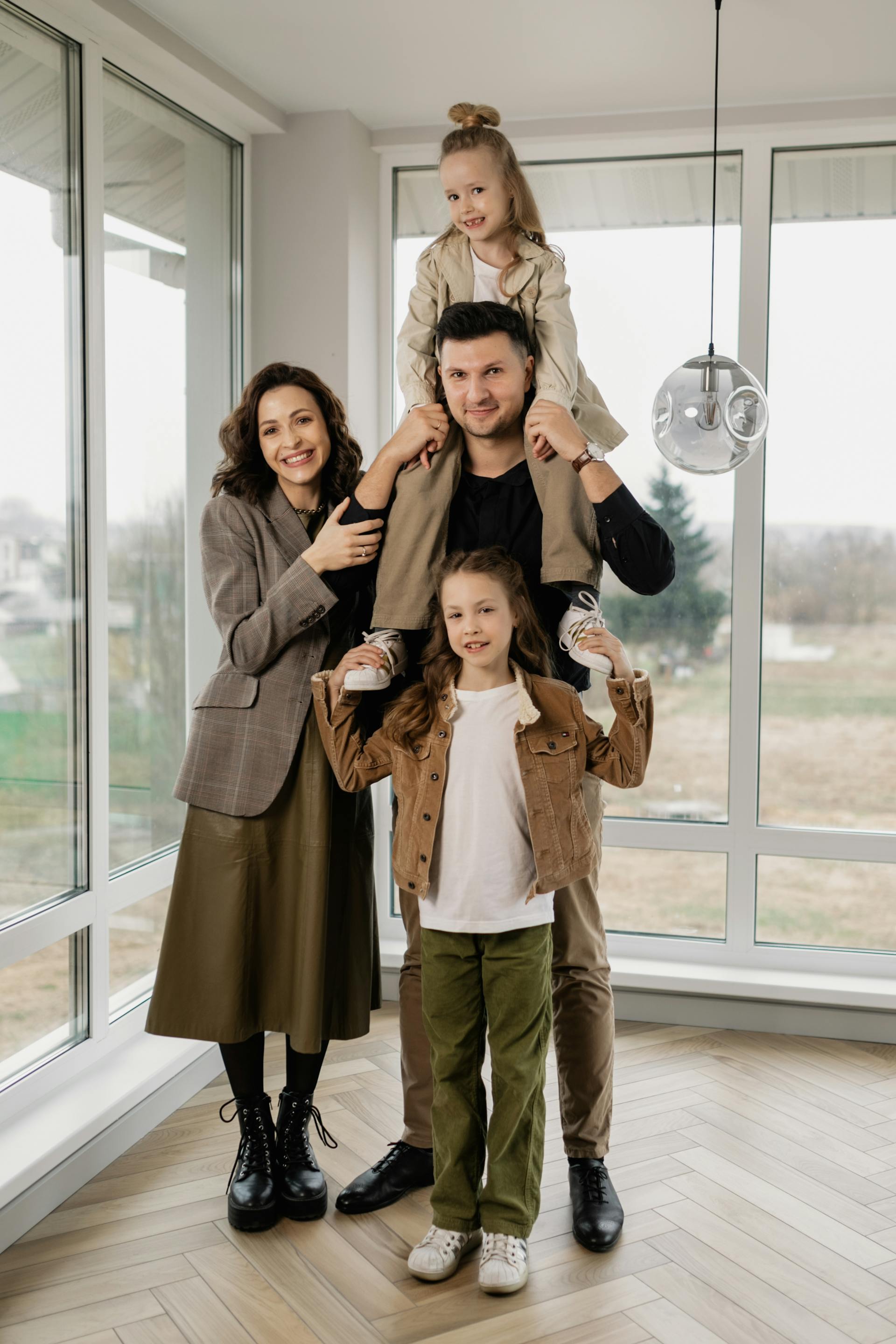 A man carrying a girl on his shoulders while standing beside his wife and daughter | Source: Pexels