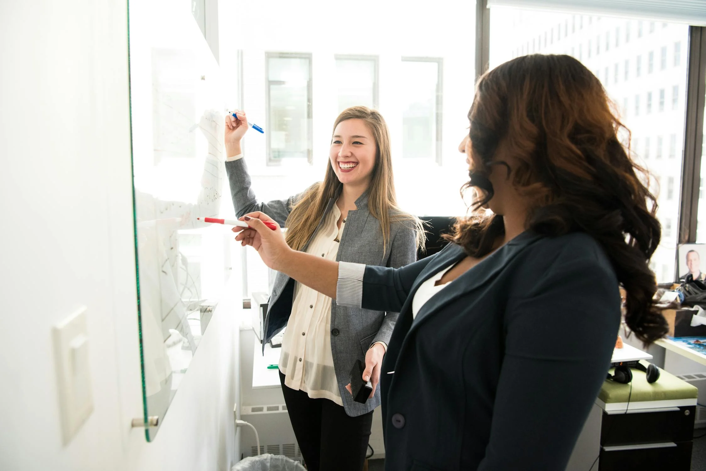 Women writing on a board in an office | Source: Pexels