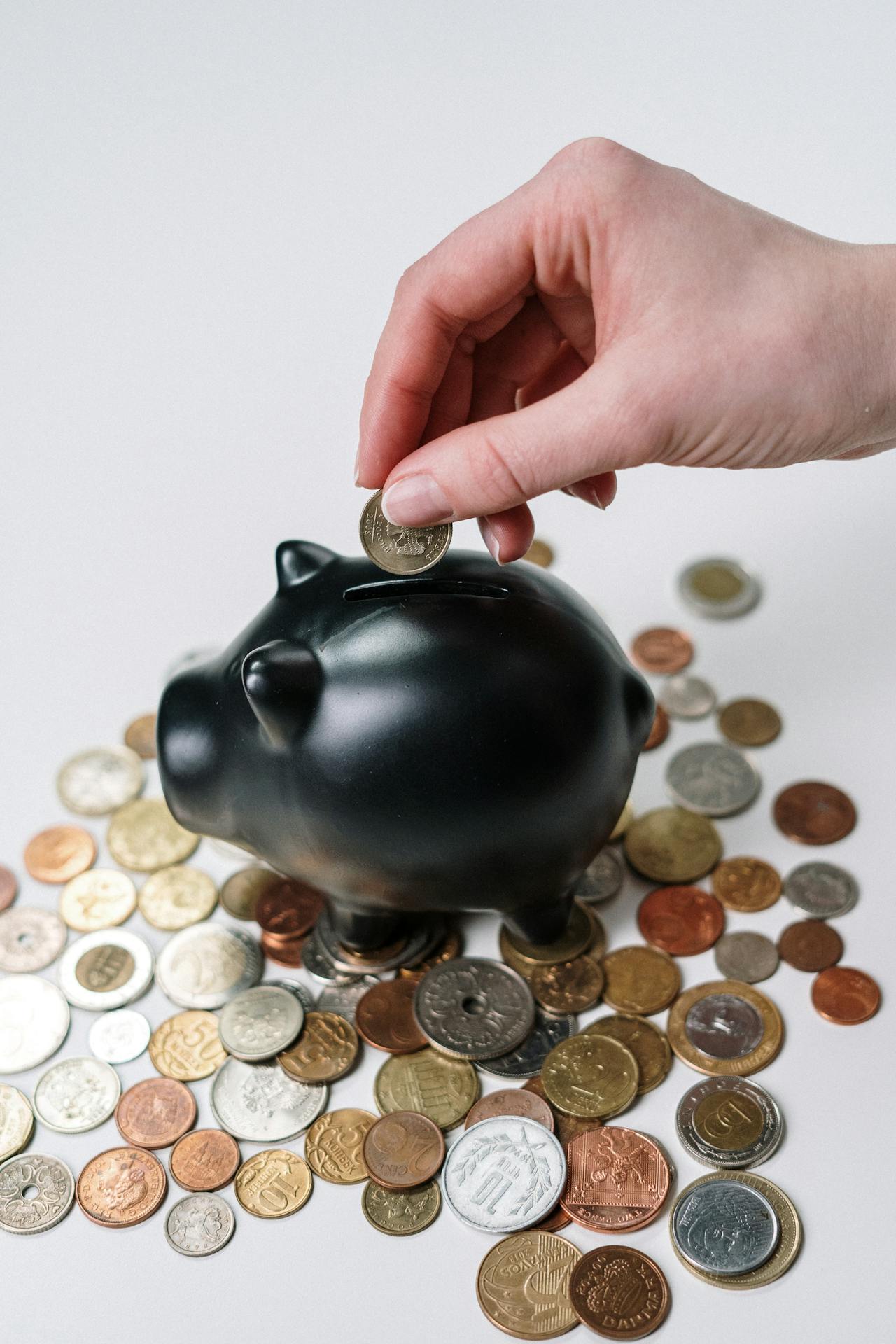 Close-up shot of a woman putting a coin in a piggy bank | Source: Pexels