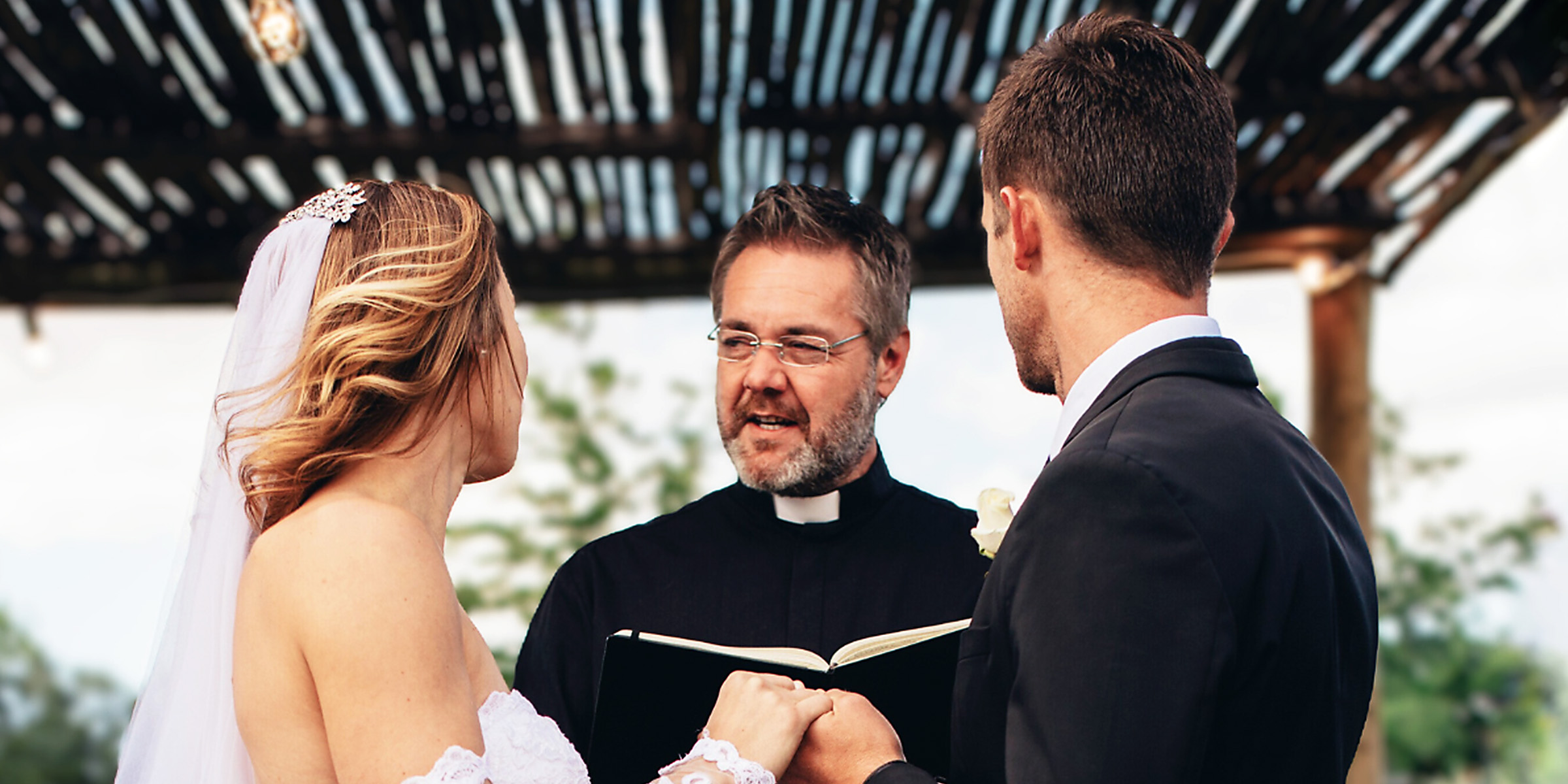 A bride and groom facing a priest | Source: Shutterstock