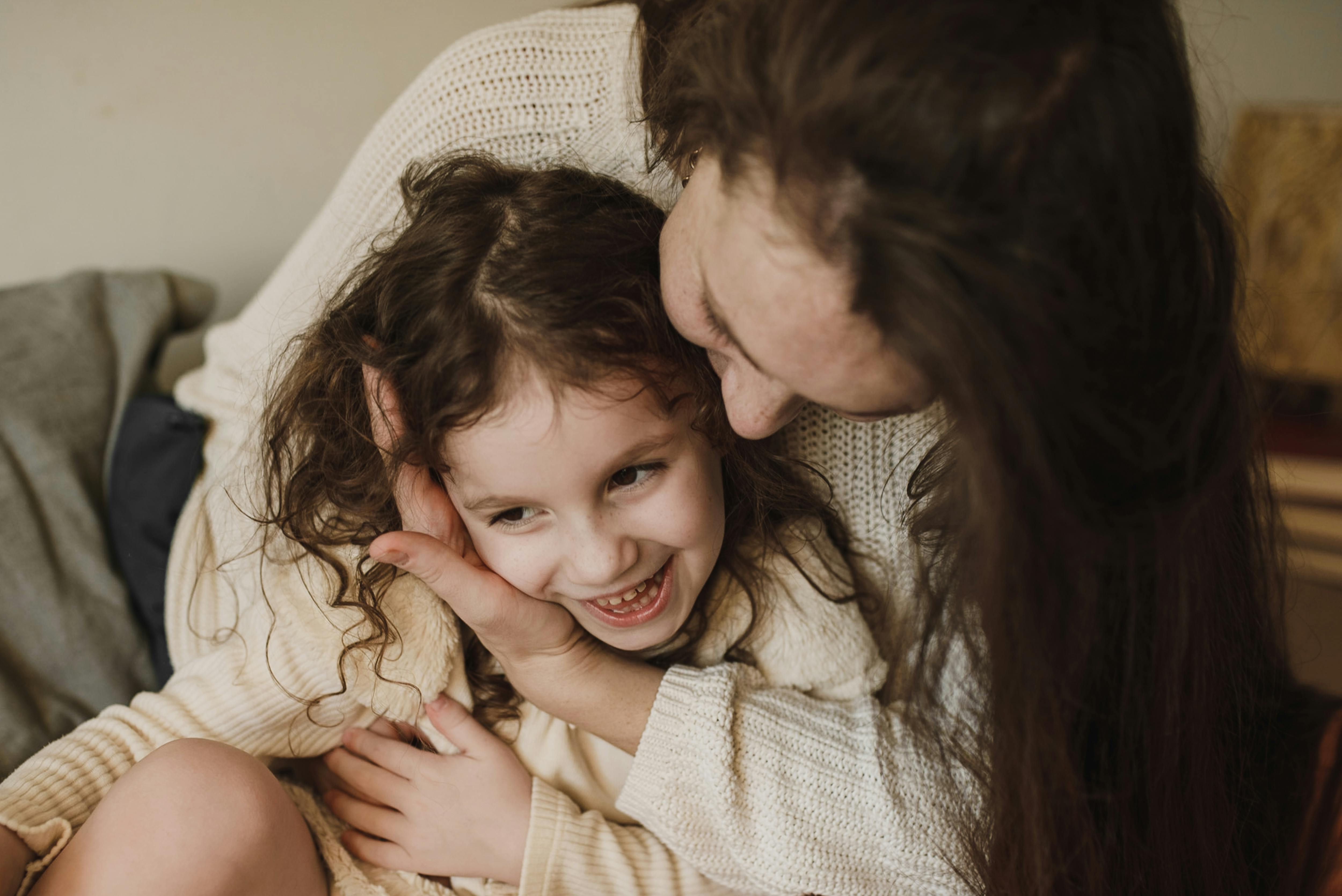 A happy girl sitting in her mother's lap | Source: Pexels