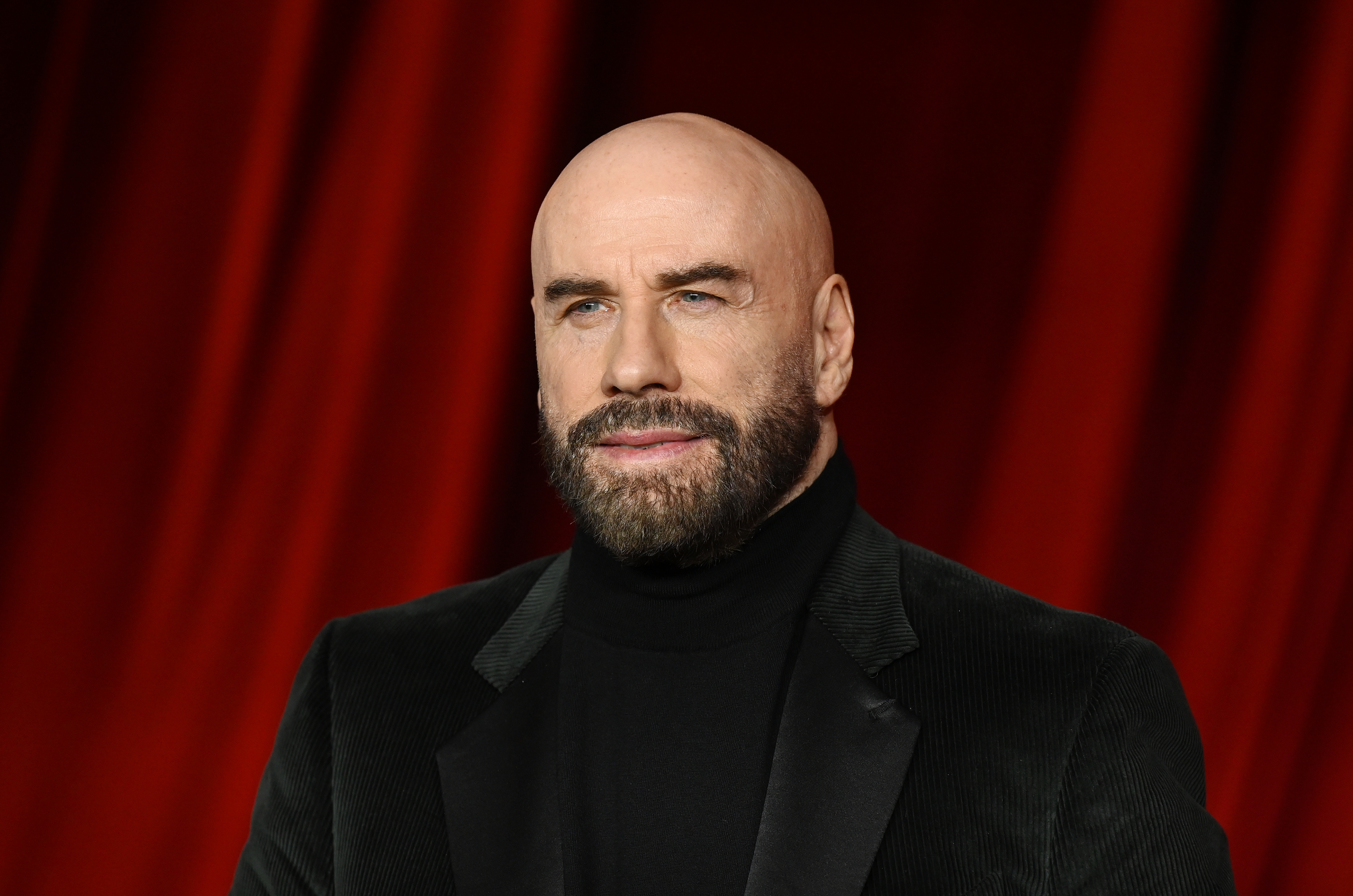 Travolta, also 71, attended the Academy Museum Gala in Los Angeles with a strikingly different presence. Dressed in a black turtleneck and matching velvet blazer, his shaved head and full beard gave him a bold, sculpted look. With a piercing gaze and polished styling, he leaned into a sleeker, more stylized version of age — one that demanded attention.