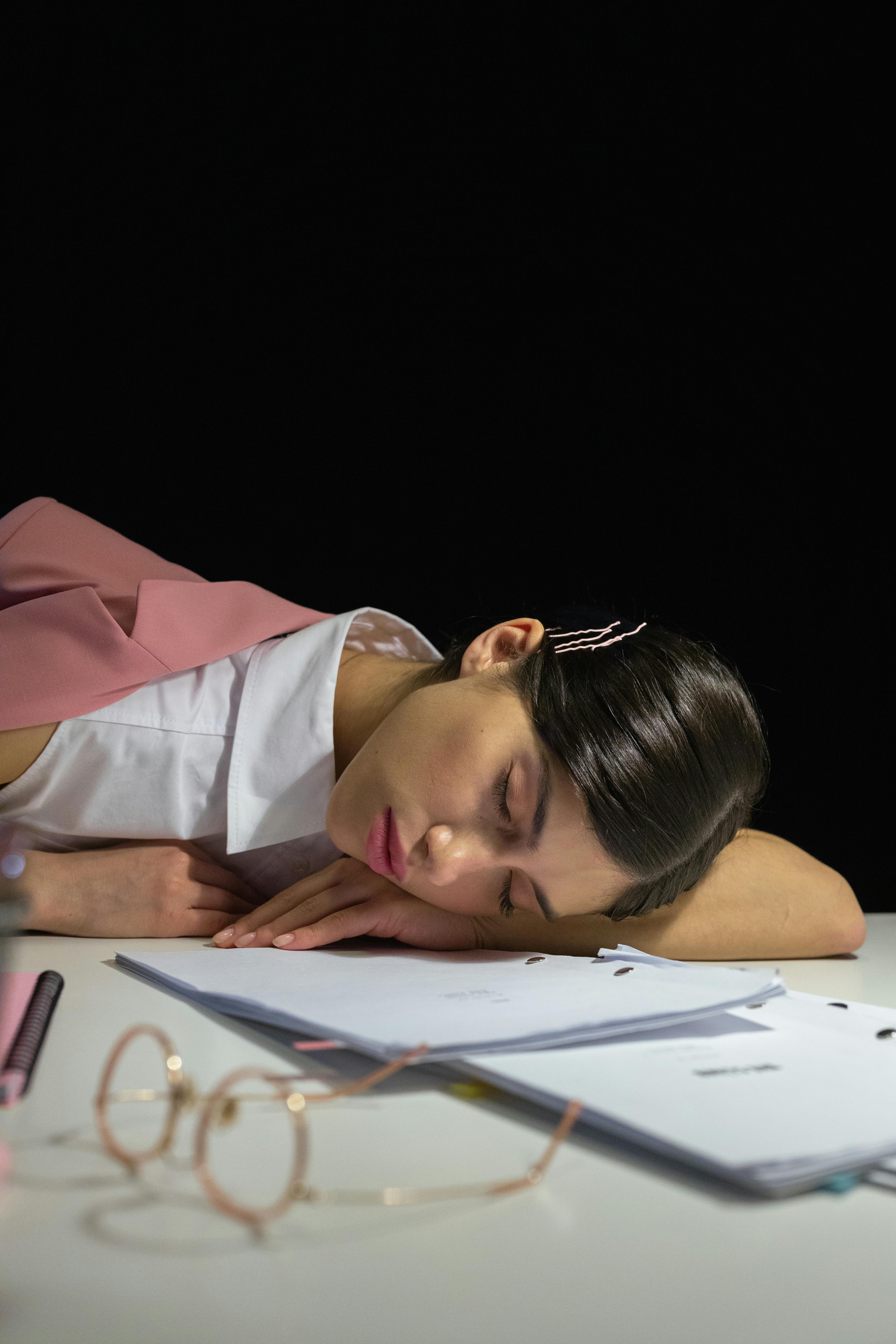 A tired woman sleeping on her desk | Source: Pexels