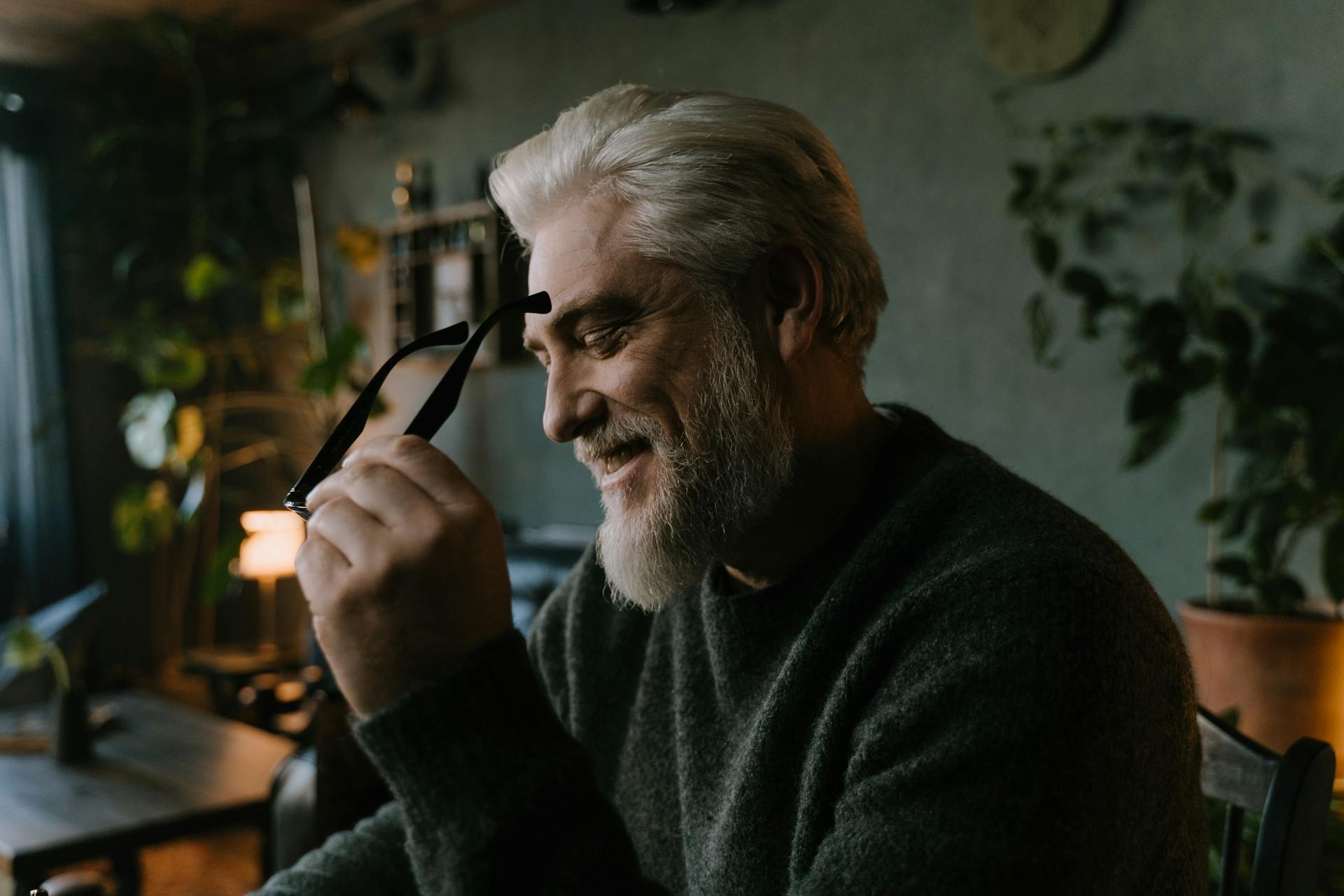 An older man holding his eyeglasses and laughing | Source: Pexels