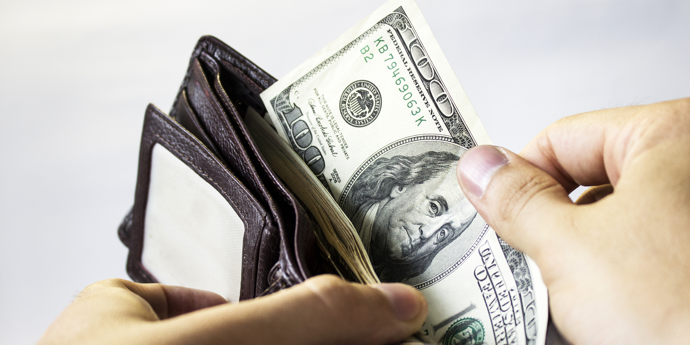 A person taking out US Dollars from a wallet | Source: Shutterstock