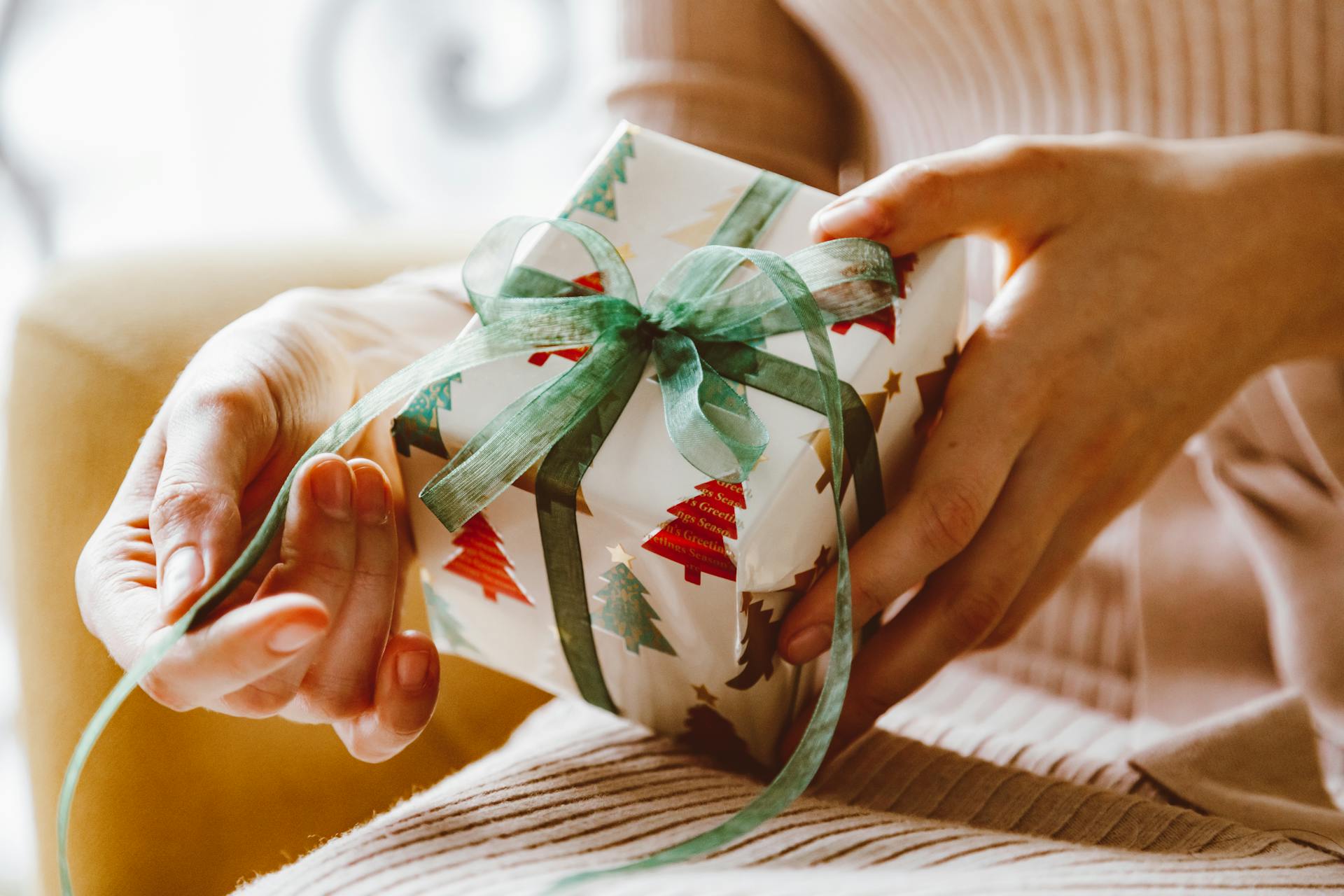 Um close-up das mãos de uma mulher prestes a desembrulhar um presente de Natal | Fonte: Pexels