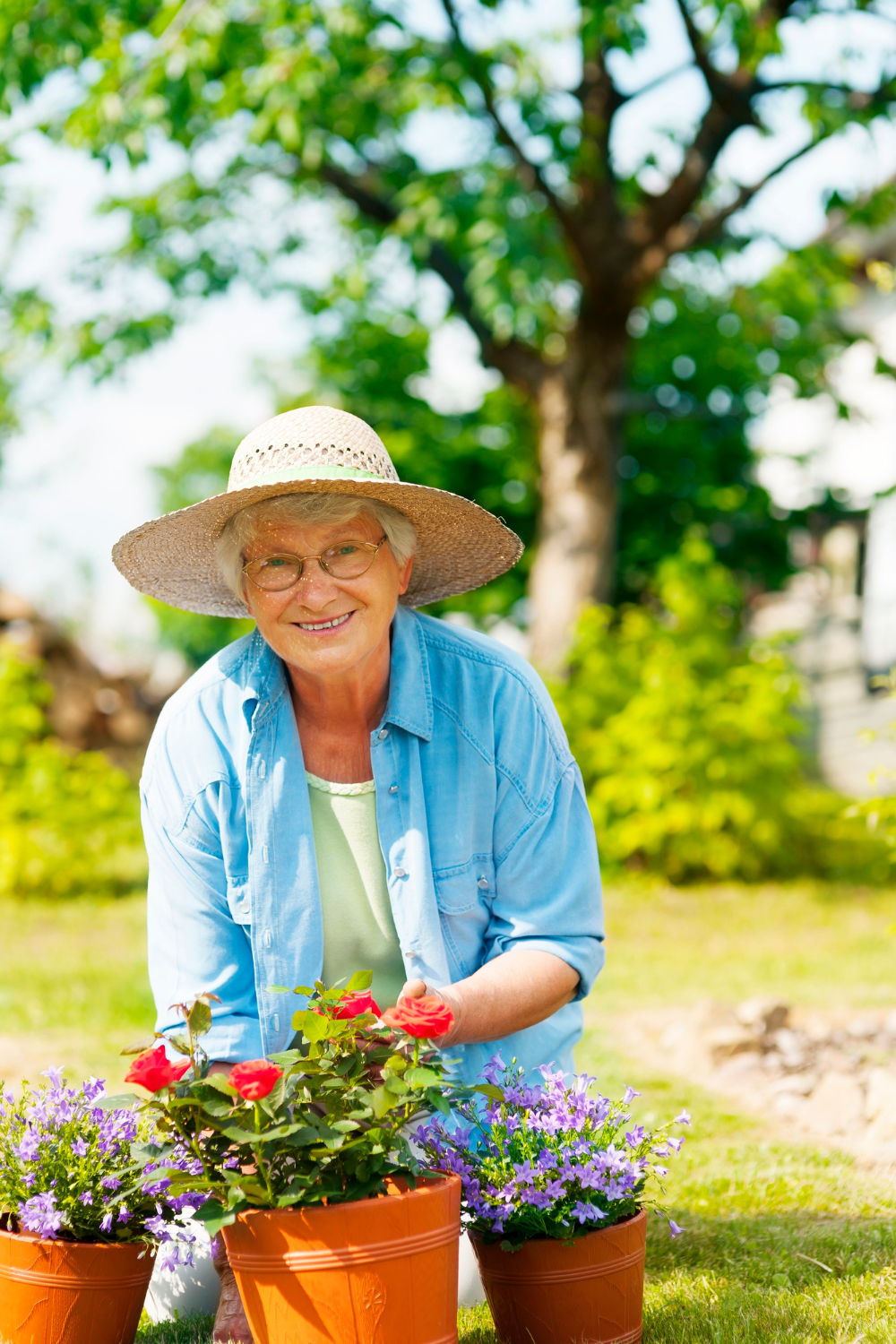 A smiling elderly woman tending to her potted plants | Source: Freepik