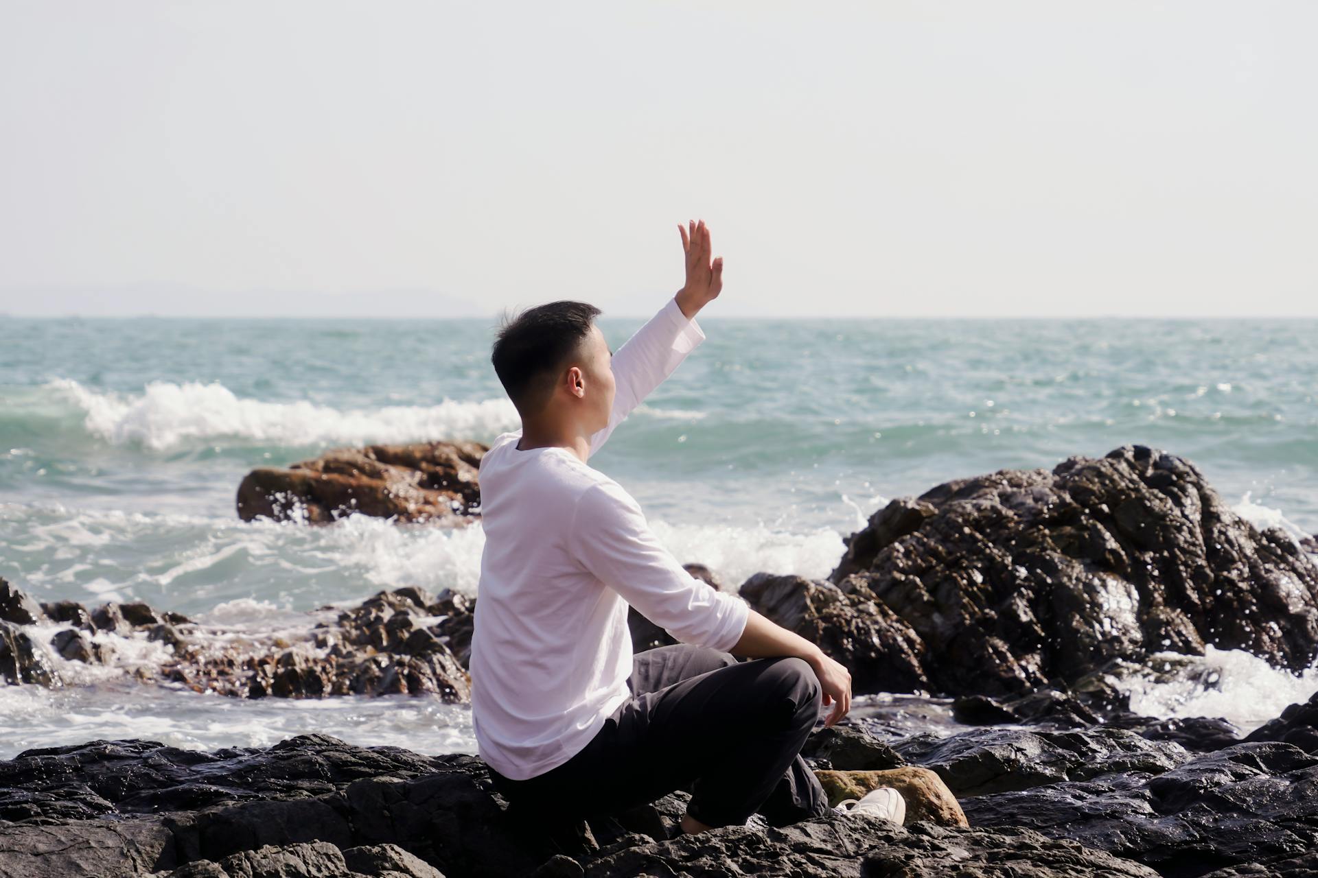 A man sitting on a rocky beach | Source: Pexels