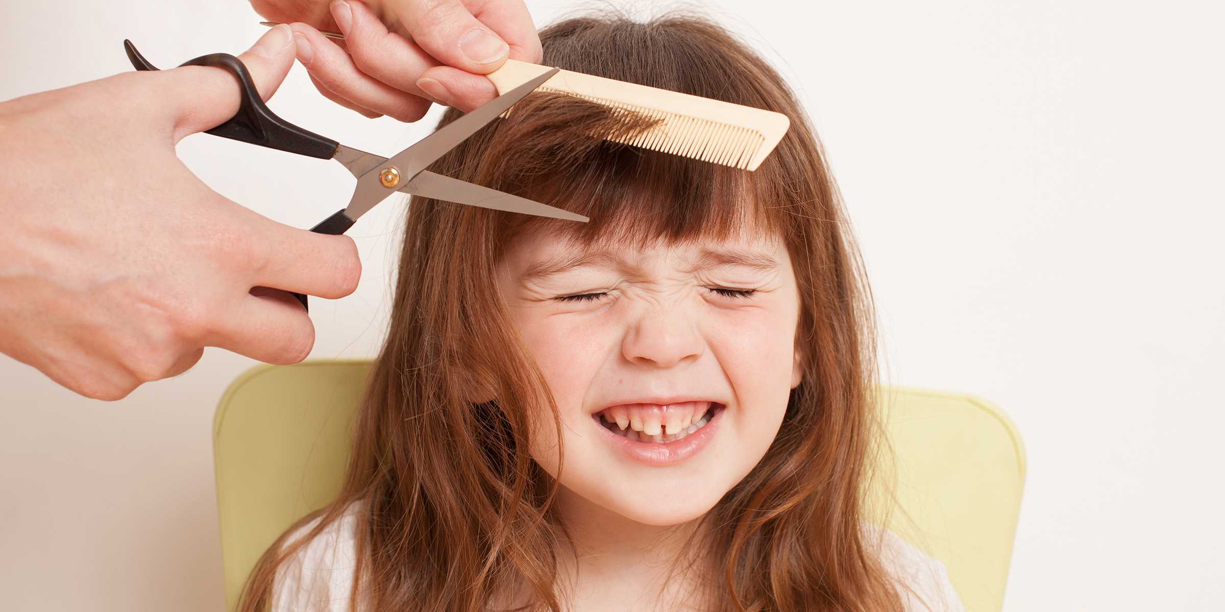 A person cutting a little girl's hair | Source: Shutterstock