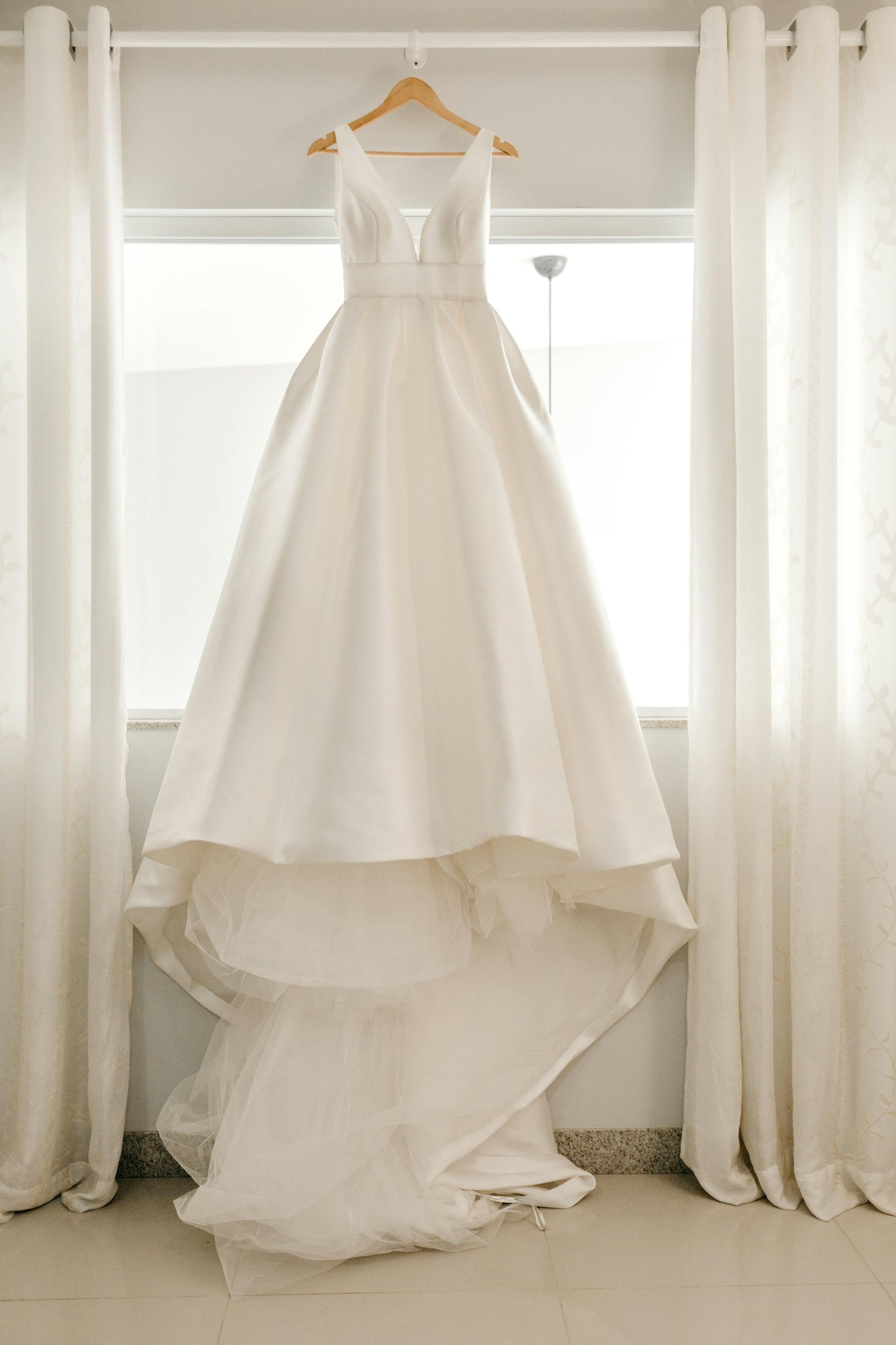 A wedding dress hanging on a curtain rod | Source: Pexels