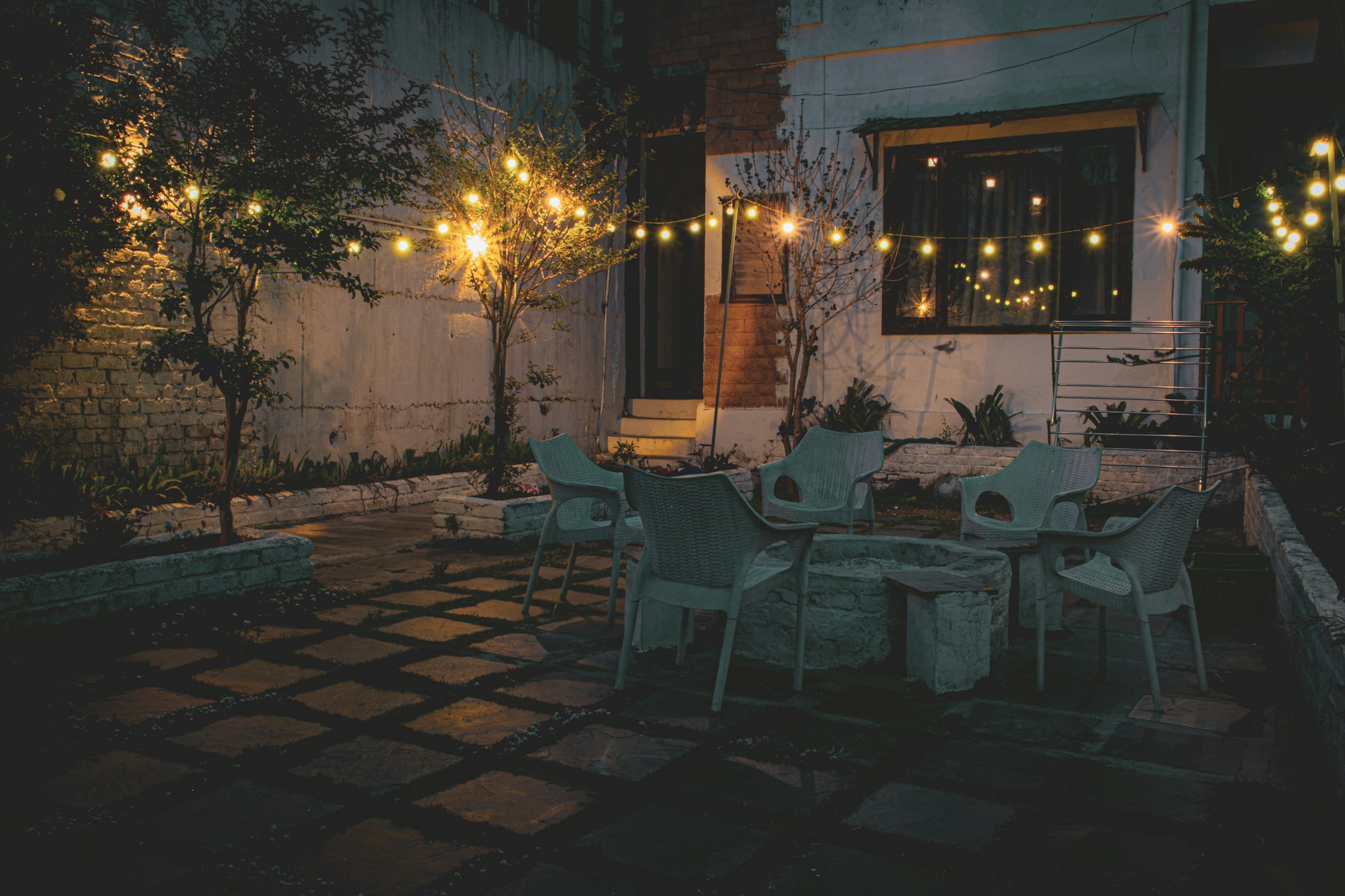 A distant view of a patio with yellow lights, tables, and chairs | Source: Unsplash