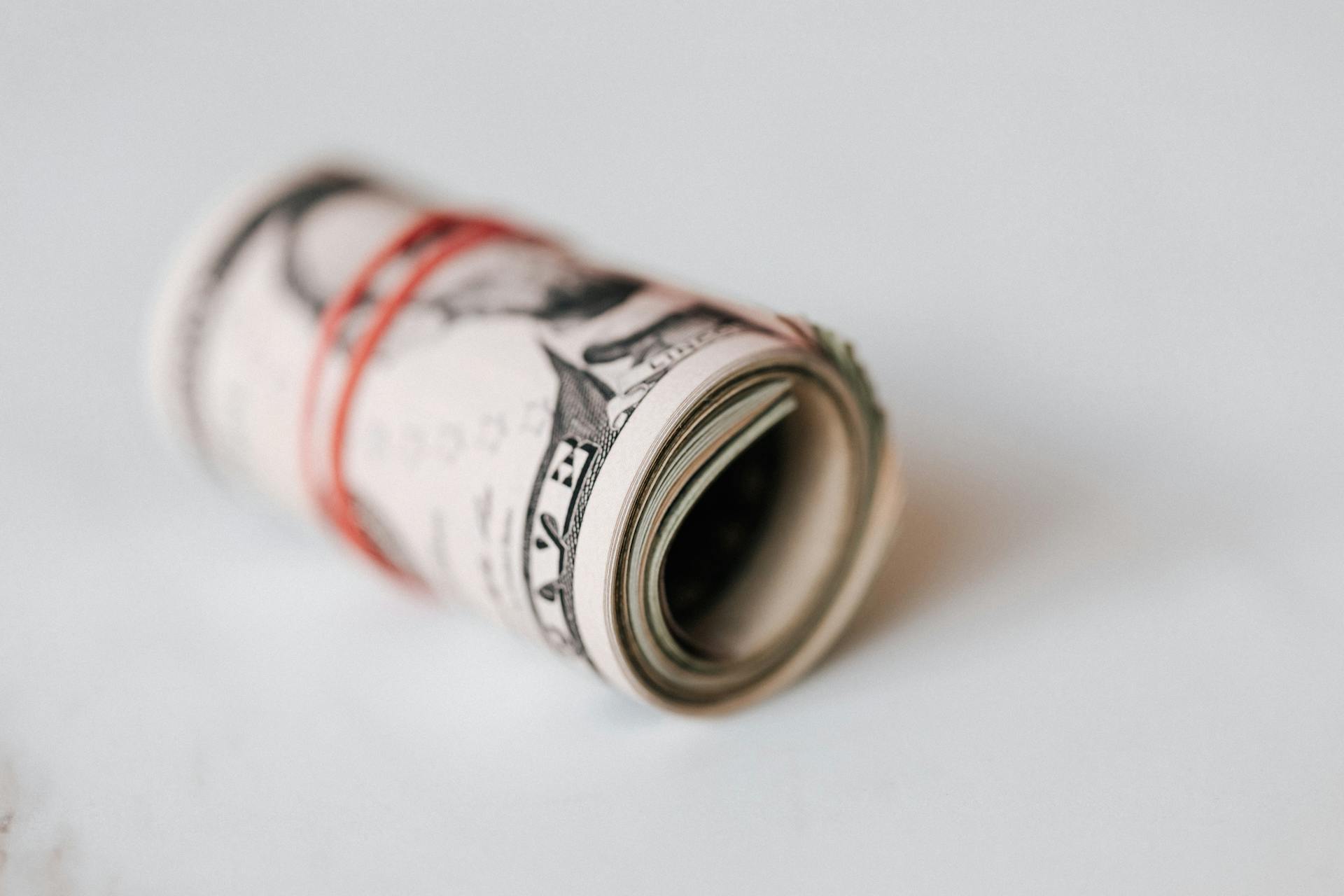 A red rubber band wound around rolled dollar bills | Source: Pexels