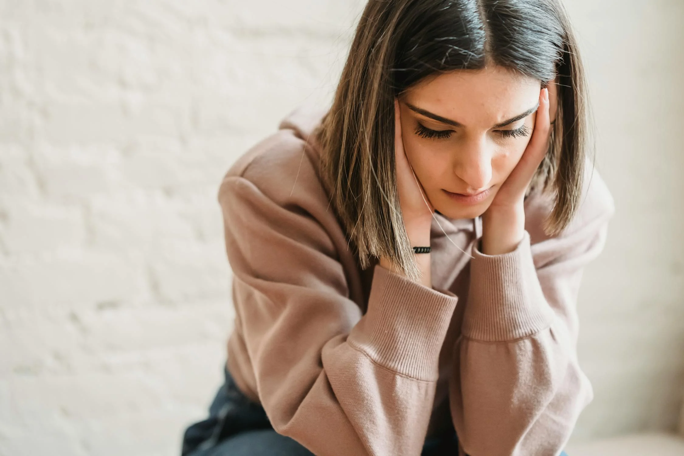 A sad woman sitting with her eyes closed ⏐ Source: Pexels