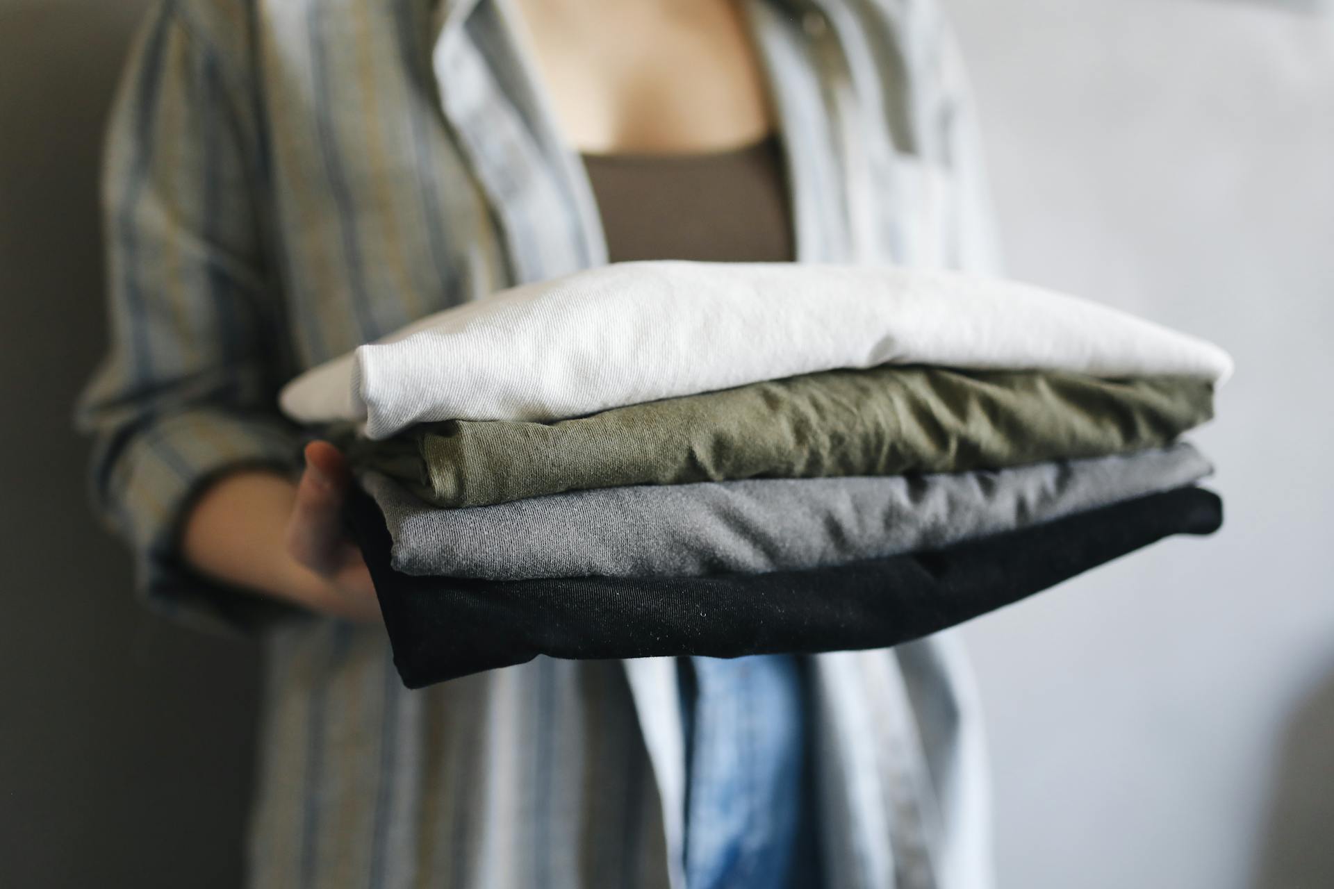 A close-up shot of a woman holding a stack of neatly folded shirts | Source: Pexels