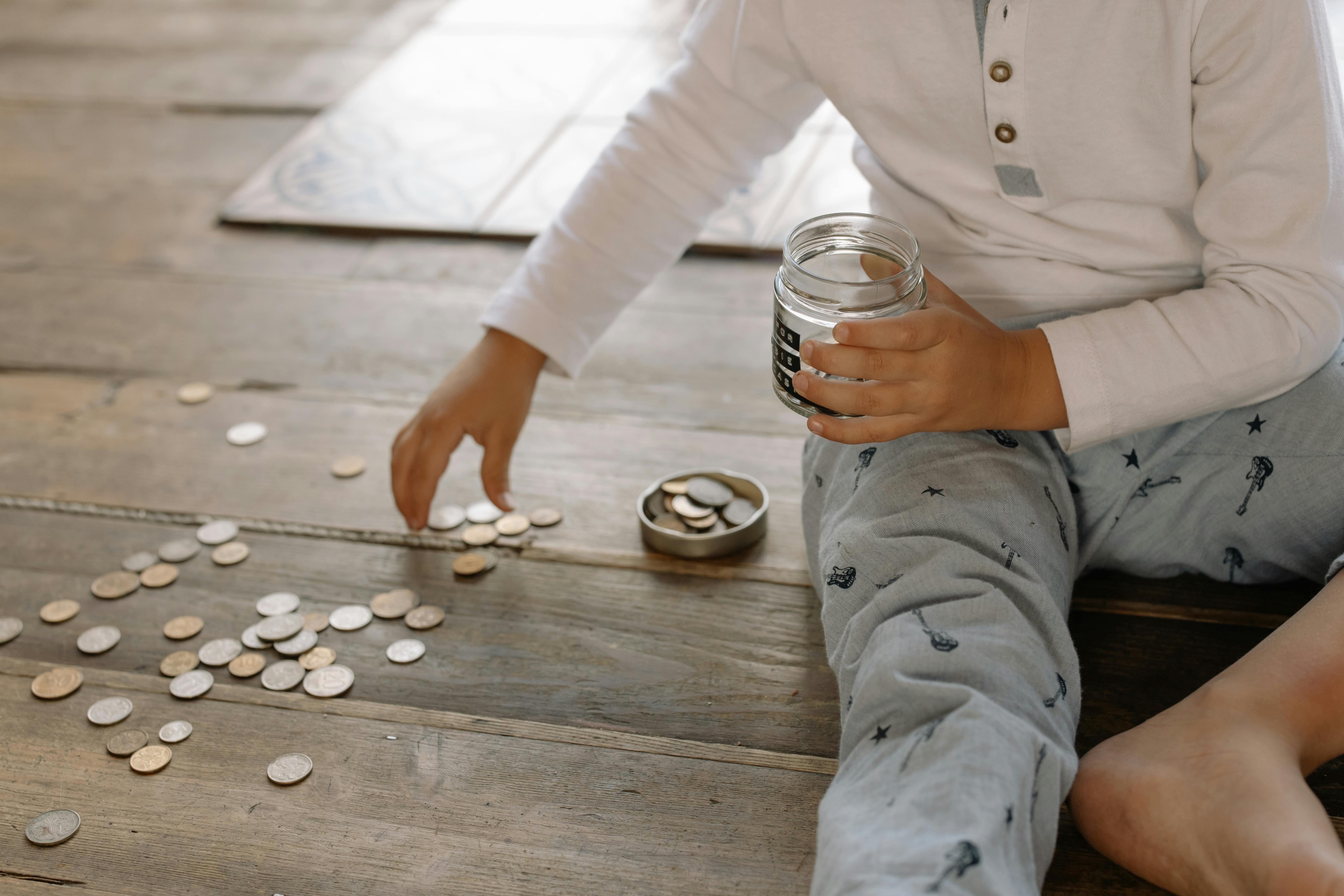A child putting coins into a glass jar | Source: Pexels