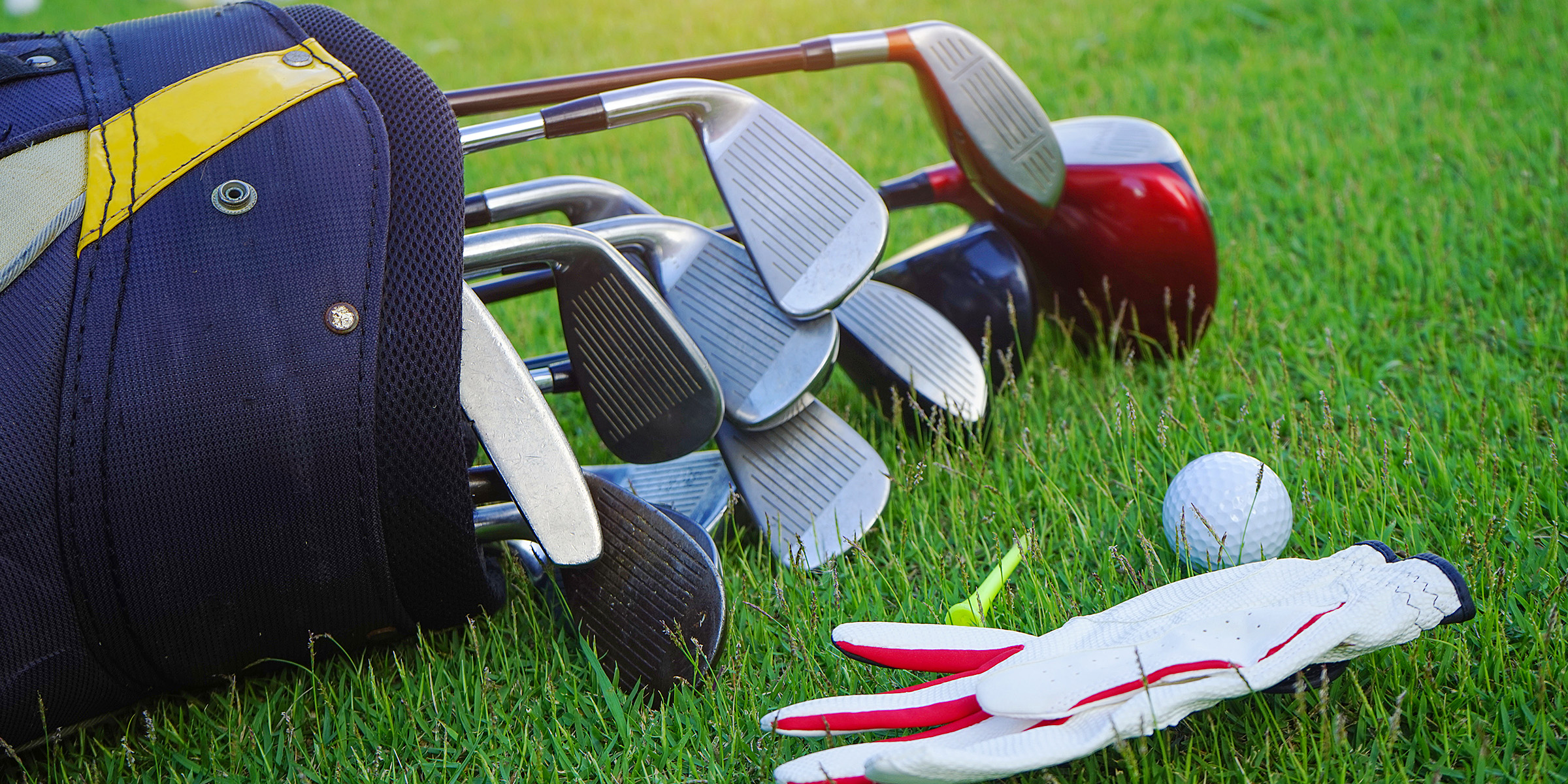 A set of golf clubs and a golf ball lying on the grass | Source: Shutterstock