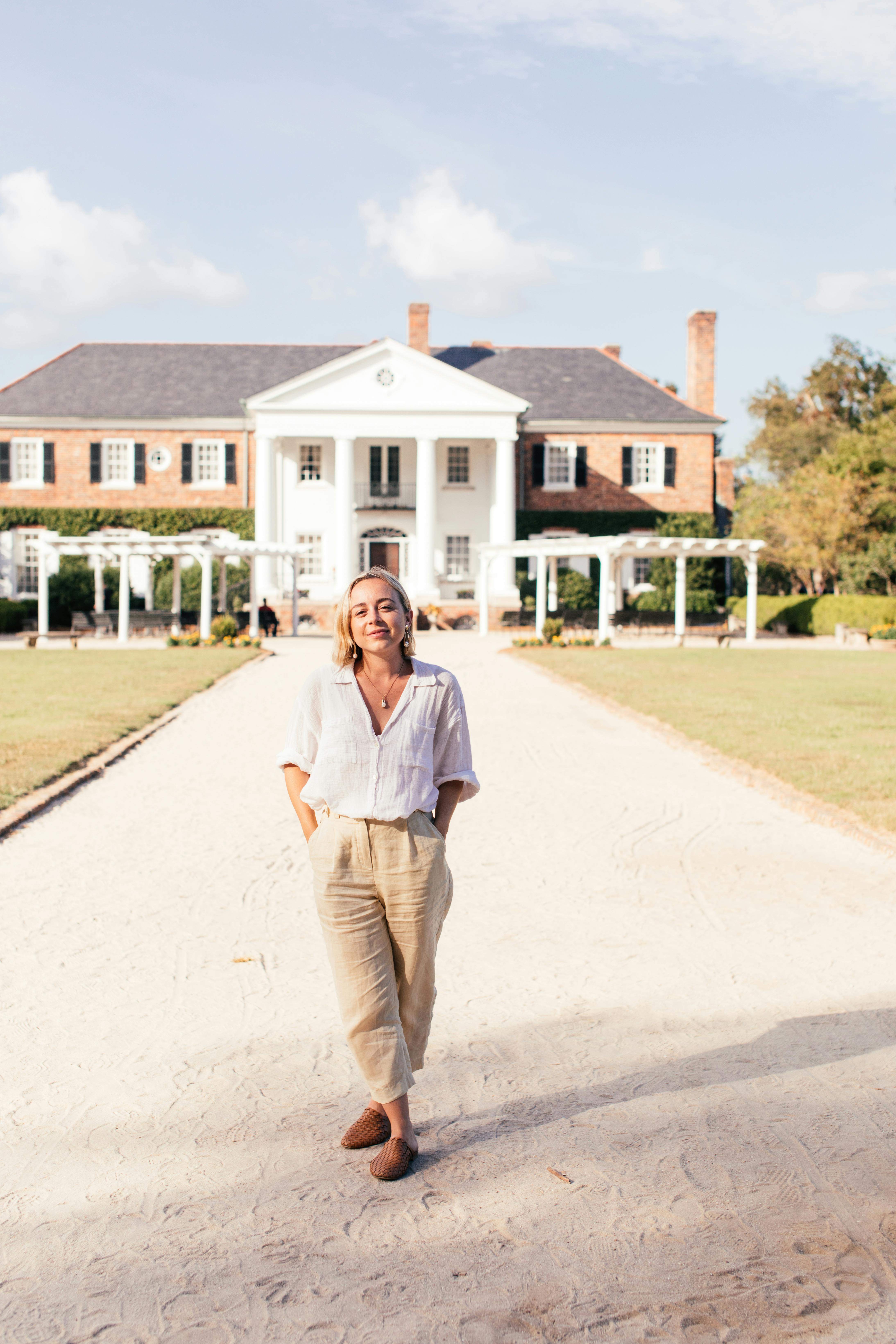 A happy woman standing in front of a mansion | Source: Pexels