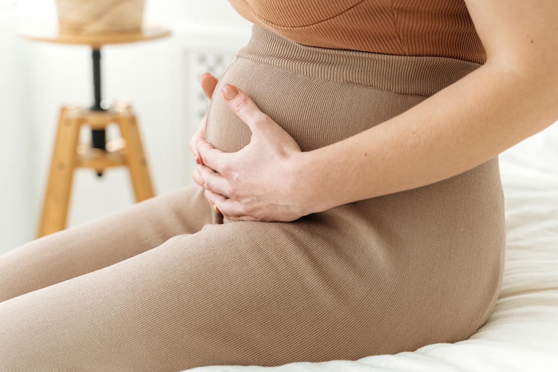 Una mujer sentada con las manos sobre su barriguita | Fuente: Pexels