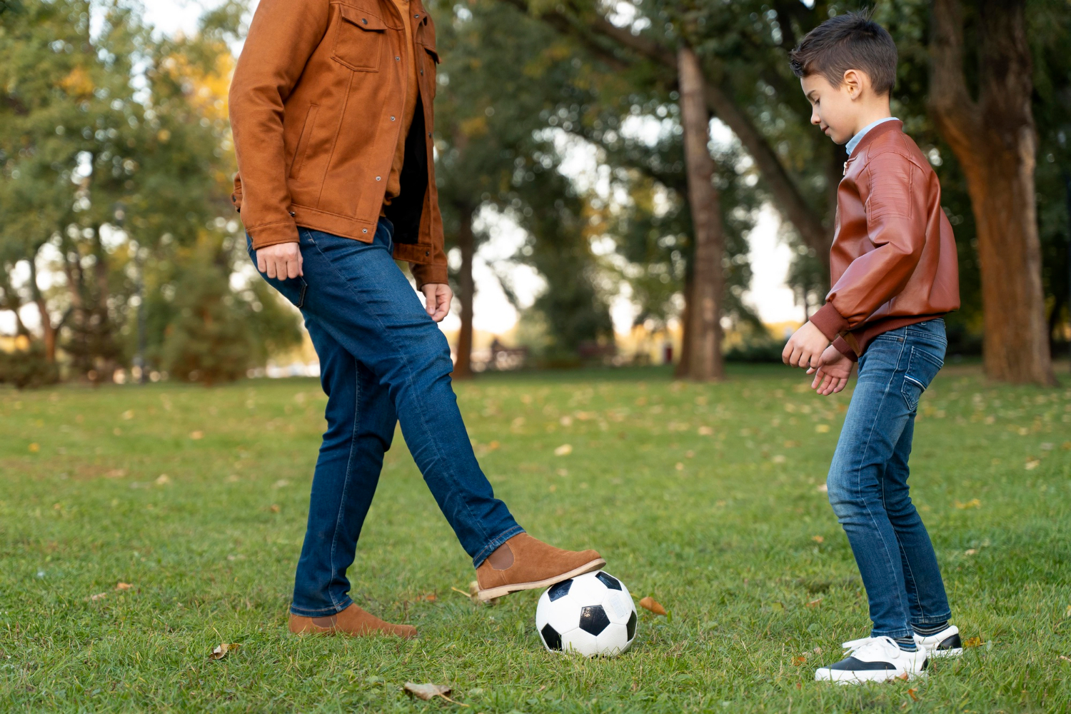 A boy playing football with his father | Source: Freepik