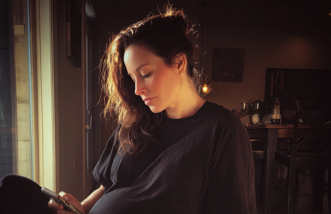 A tired woman using her phone | Source: Midjourney