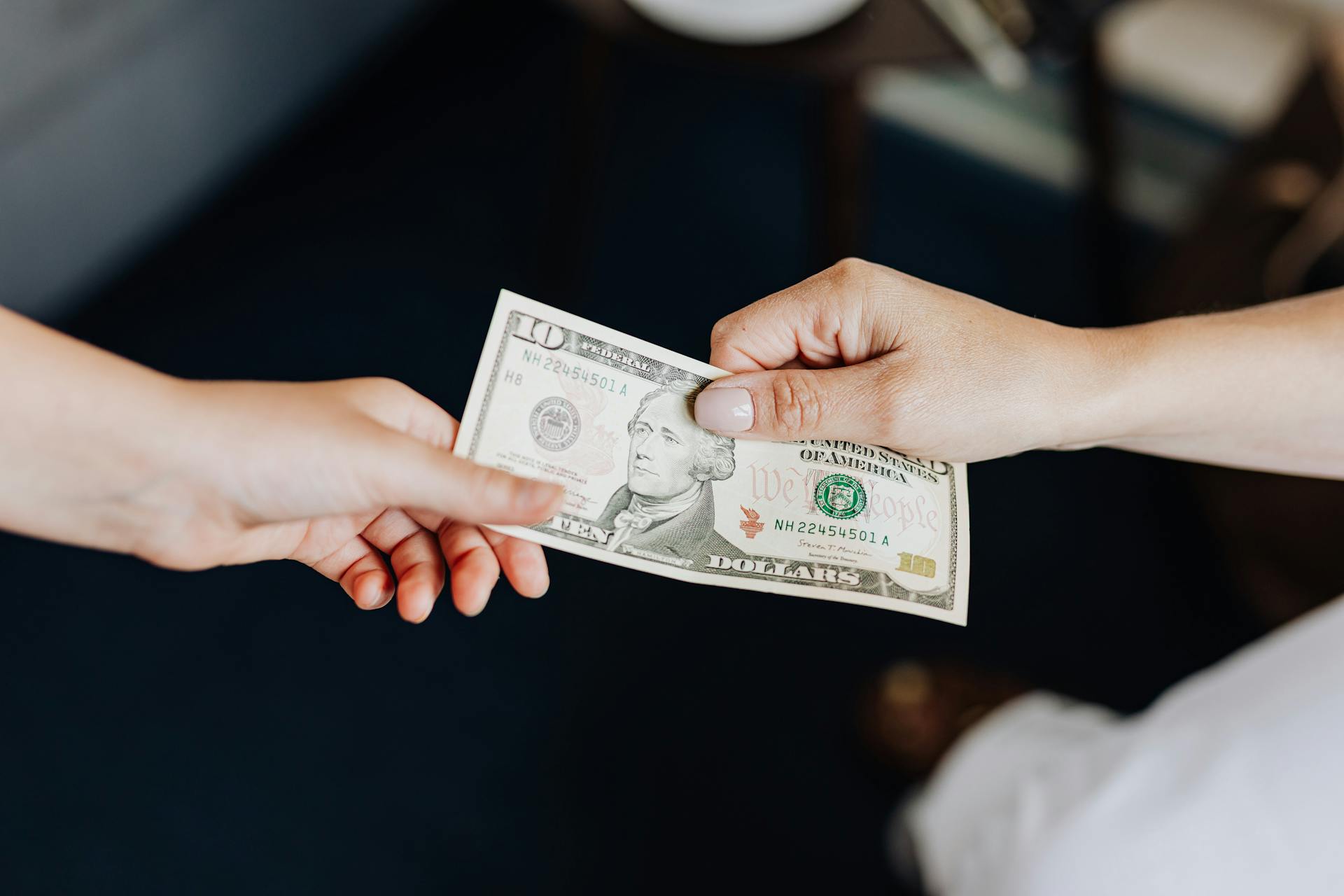 A woman giving a $10 bill to another person | Source: Pexels