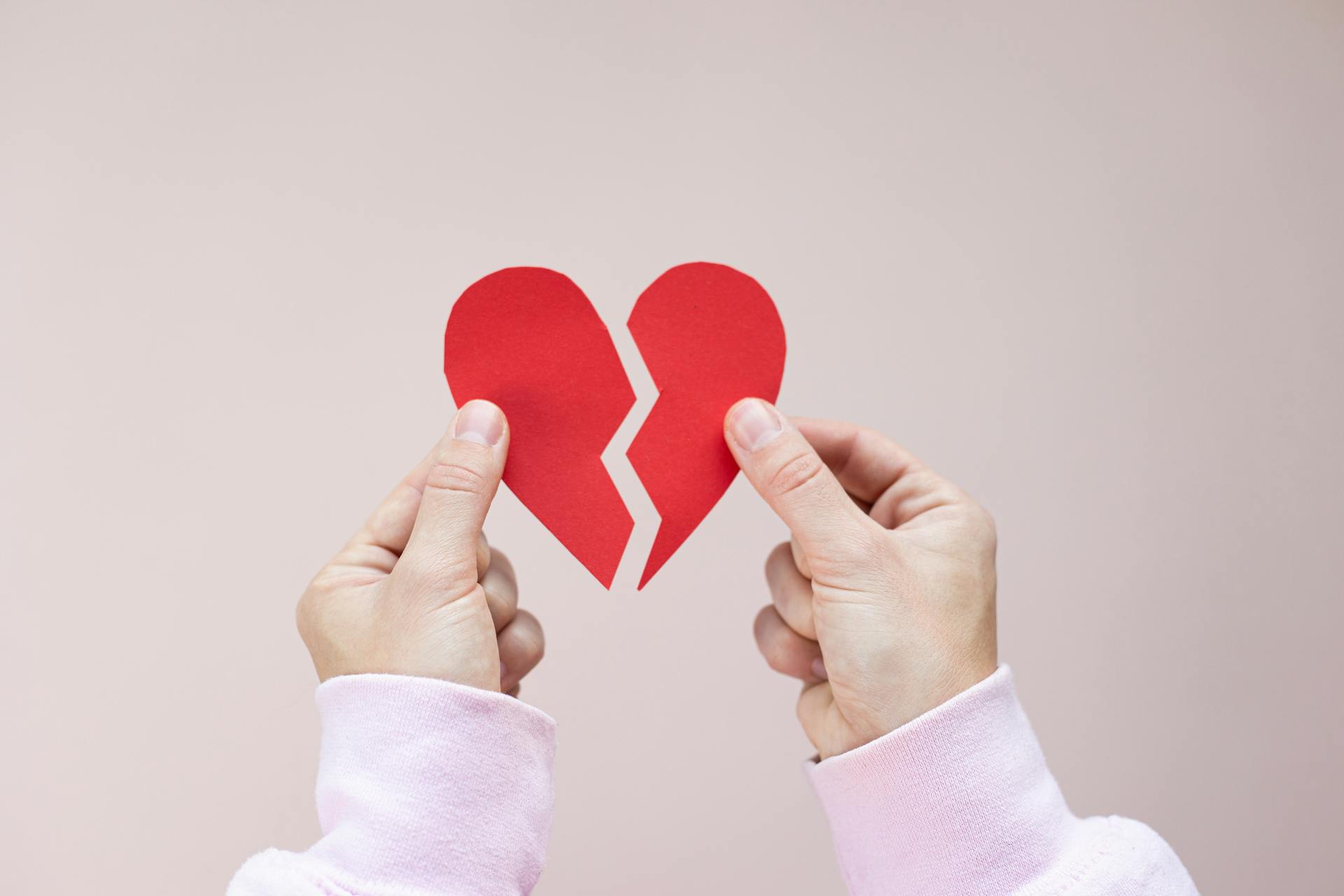 A person holding a broken red paper heart | Source: Pexels